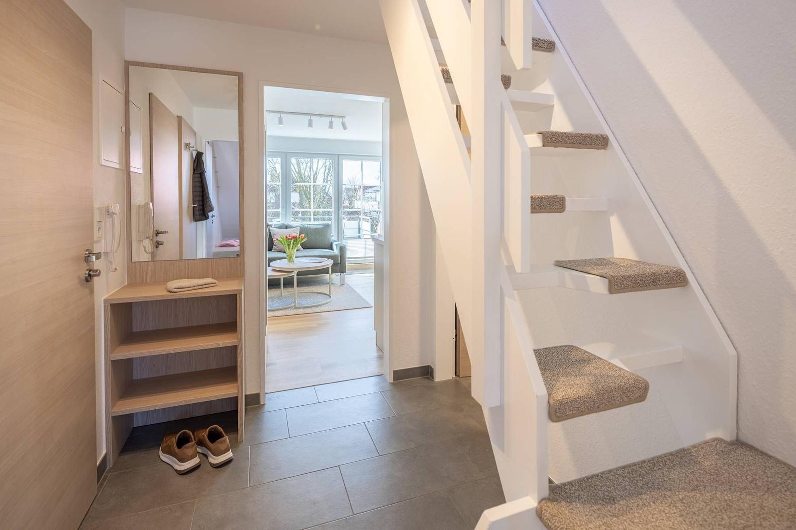 Eingangsbereich mit Garderobe, Spiegel und Treppe zur Wohnung.