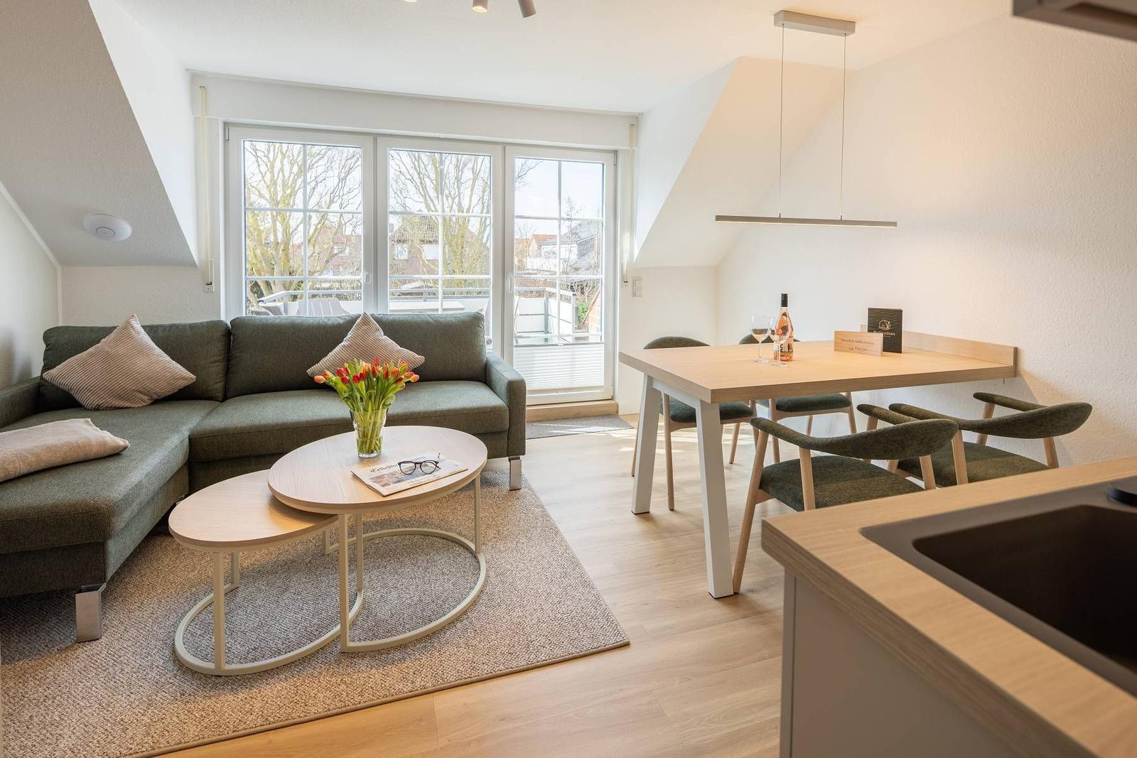 Wohn- und Essbereich mit Sofa, Tisch und Fenster zur Terrasse.