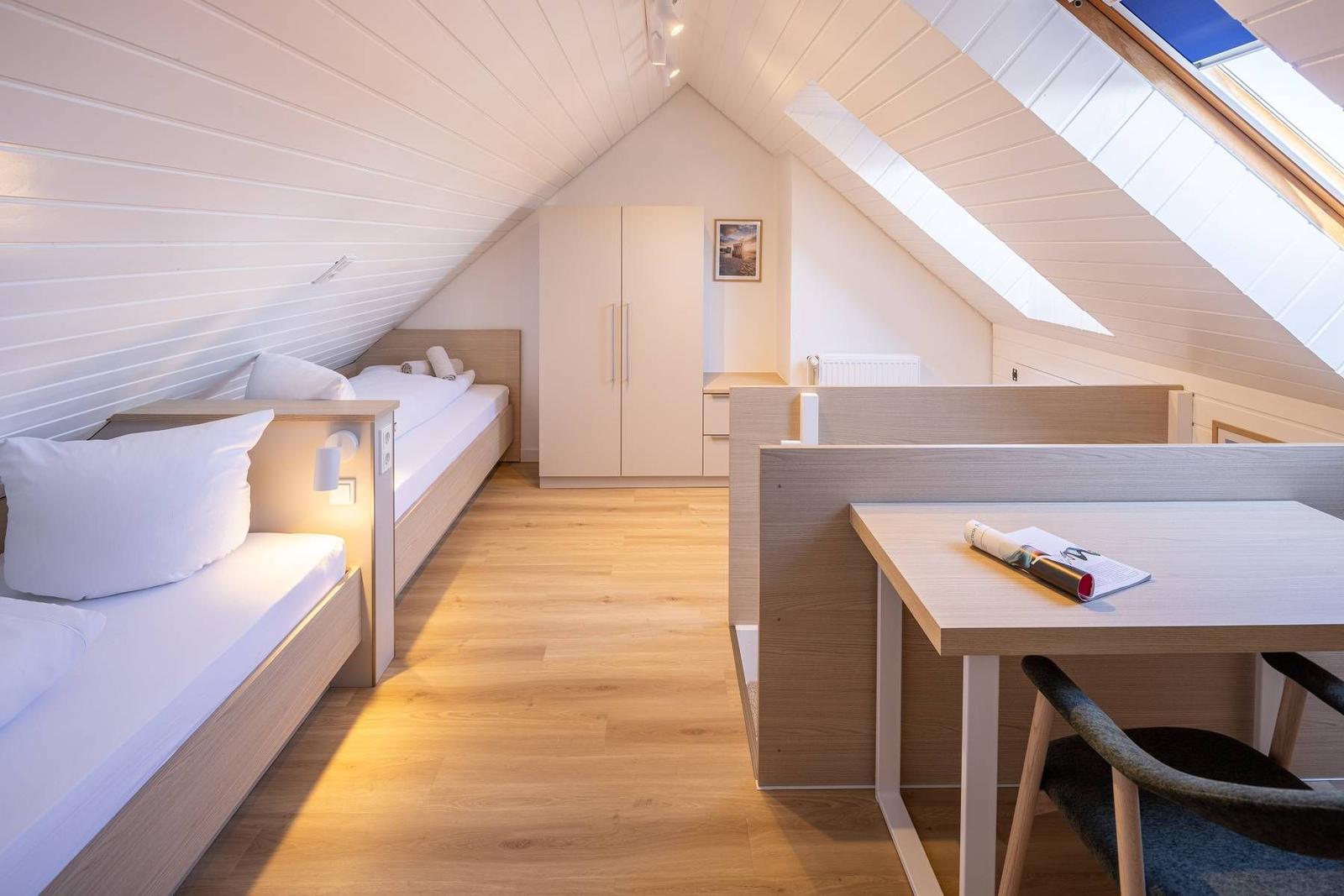 Zimmer mit zwei Betten, Schreibtisch und Dachschräge mit Fenster
