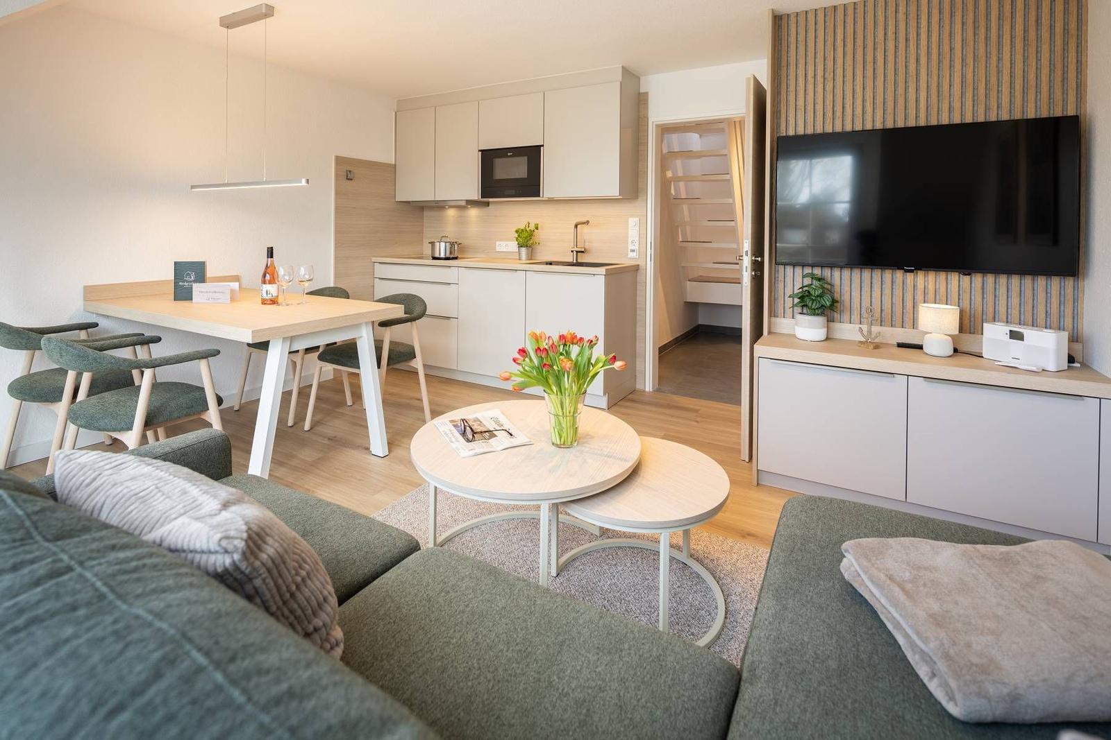 Wohnzimmer mit Essbereich, Küche und Fernseher. Einrichtung modern und funktional.