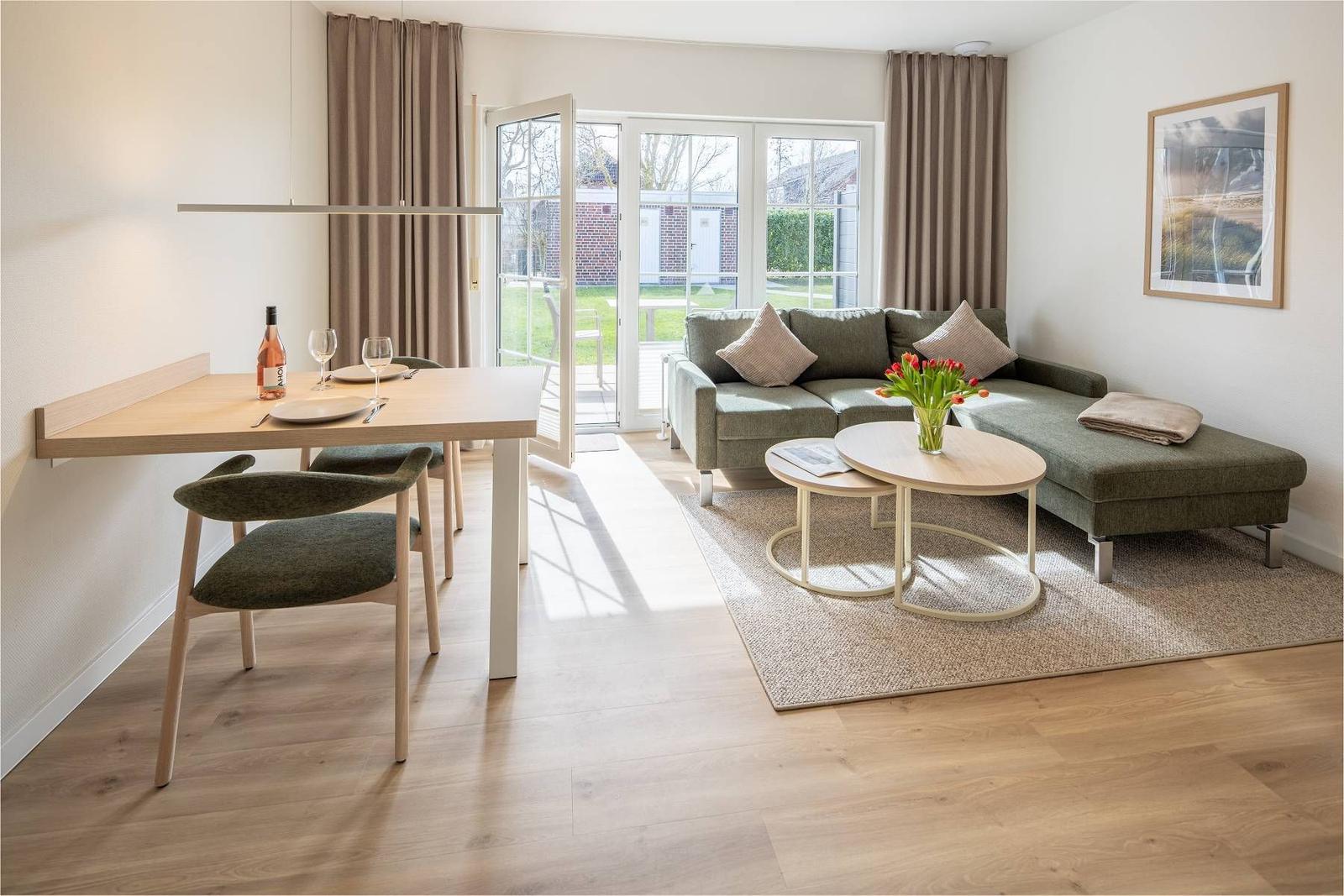 Wohn- und Essbereich mit Sofa, Tisch und Blick auf Garten.