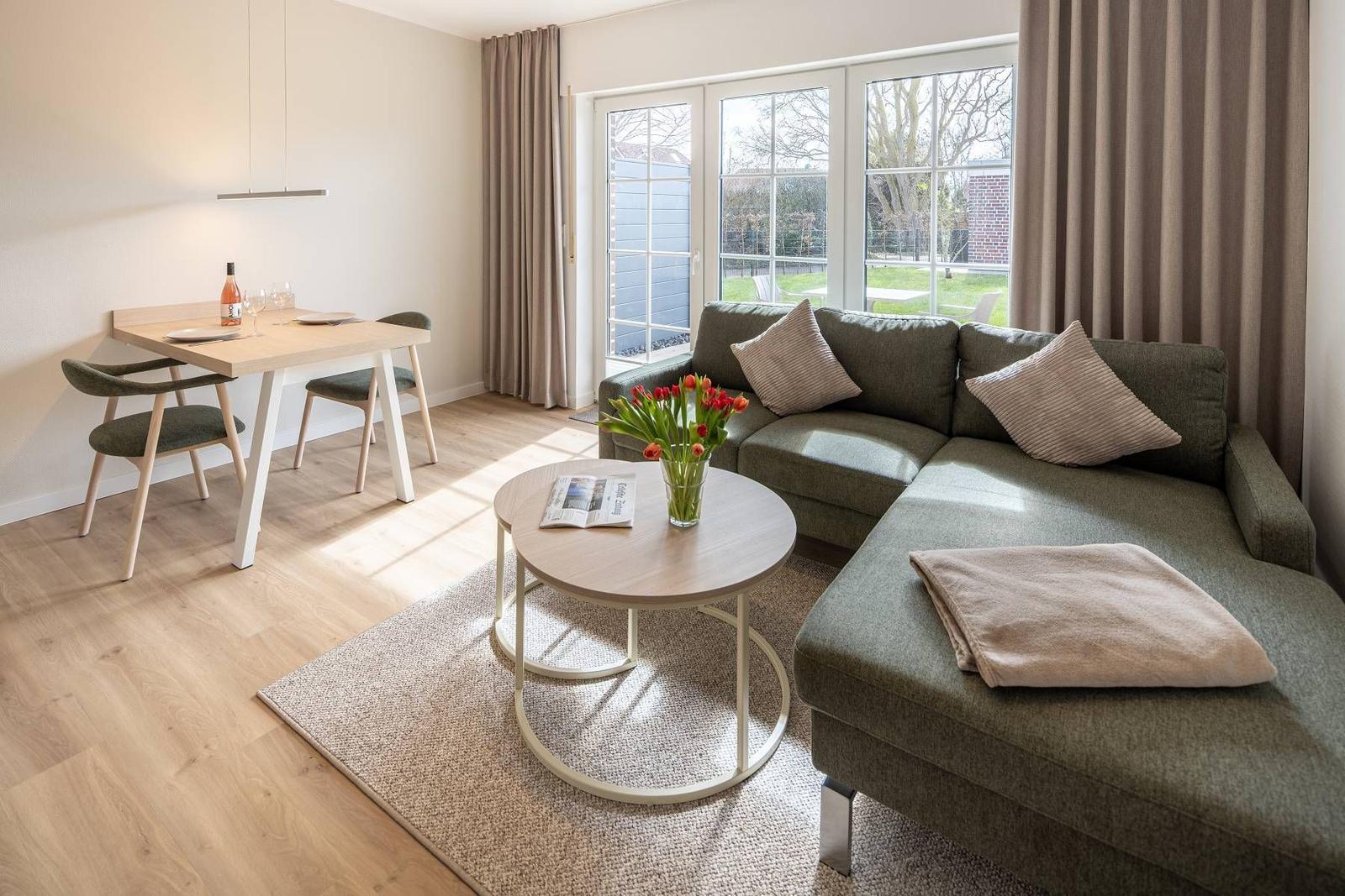 Wohnbereich mit Sofa, Esstisch und Fenster zum Garten