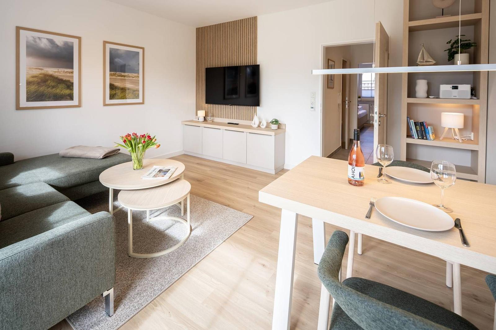 Wohn- und Essbereich mit Sofa, Esstisch und Fernseher.
