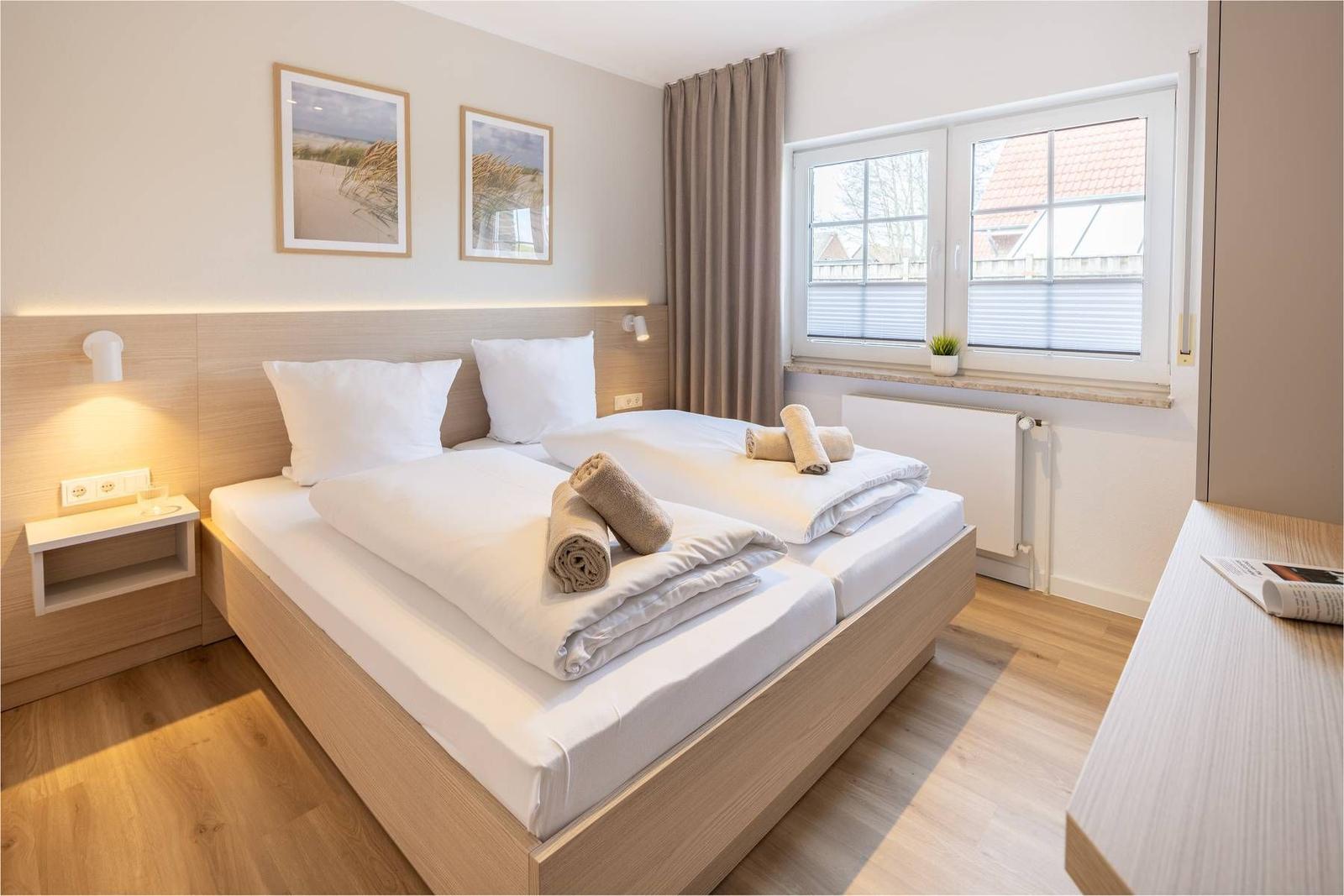 Schlafzimmer mit Doppelbett, Fenster und Holzboden.