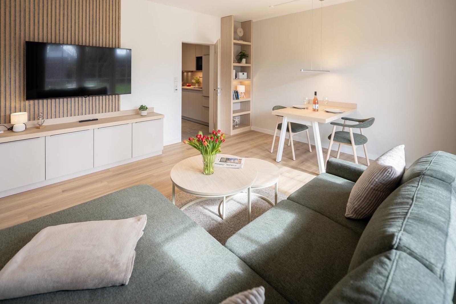 Wohnzimmer mit Sofa, Couchtisch, Fernseher und Essbereich.