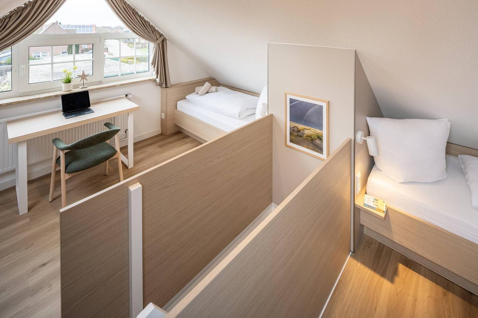 Zimmer mit zwei Betten, Schreibtisch und Fenster mit Blick.
