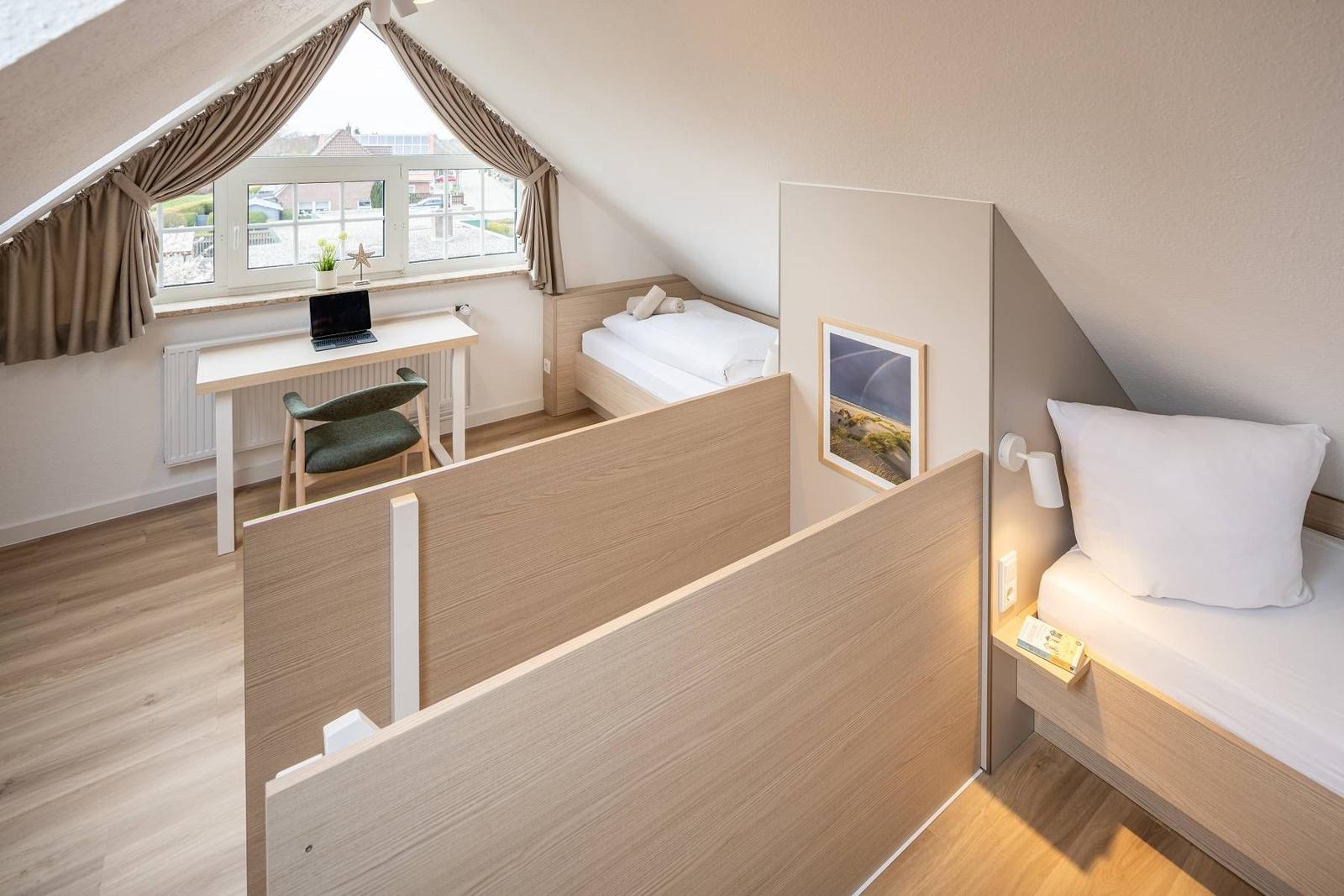 Zimmer mit zwei Betten, Schreibtisch und Fenster mit Blick nach draußen.