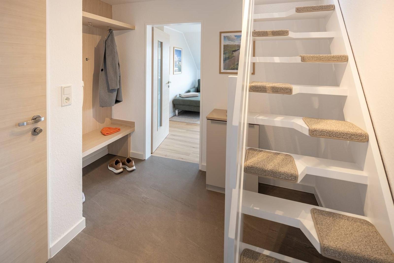 Eingangsbereich mit Garderobe, Stufen zur oberen Etage und Blick in das Schlafzimmer.
