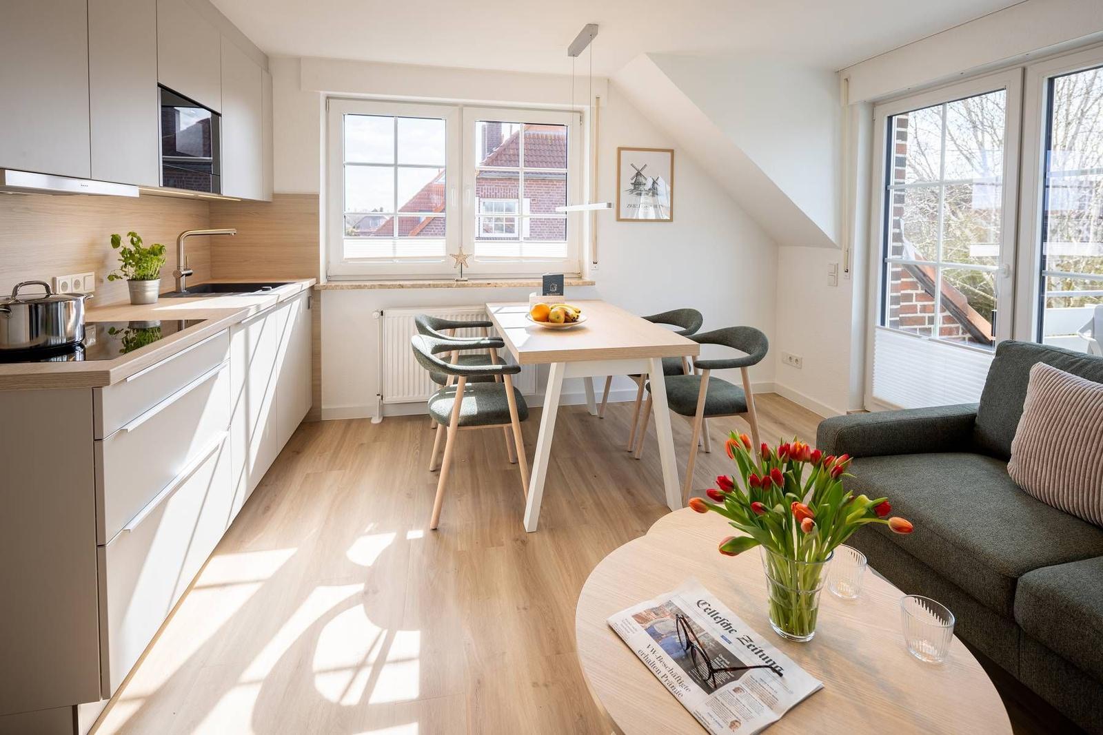Wohnküche mit Esstisch, Sofa und Fenstern. Holzboden und moderne Einrichtung.