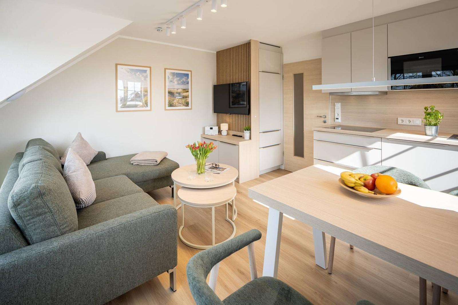 Wohn- und Küchenbereich mit Sofa, Esstisch und Küchenzeile.