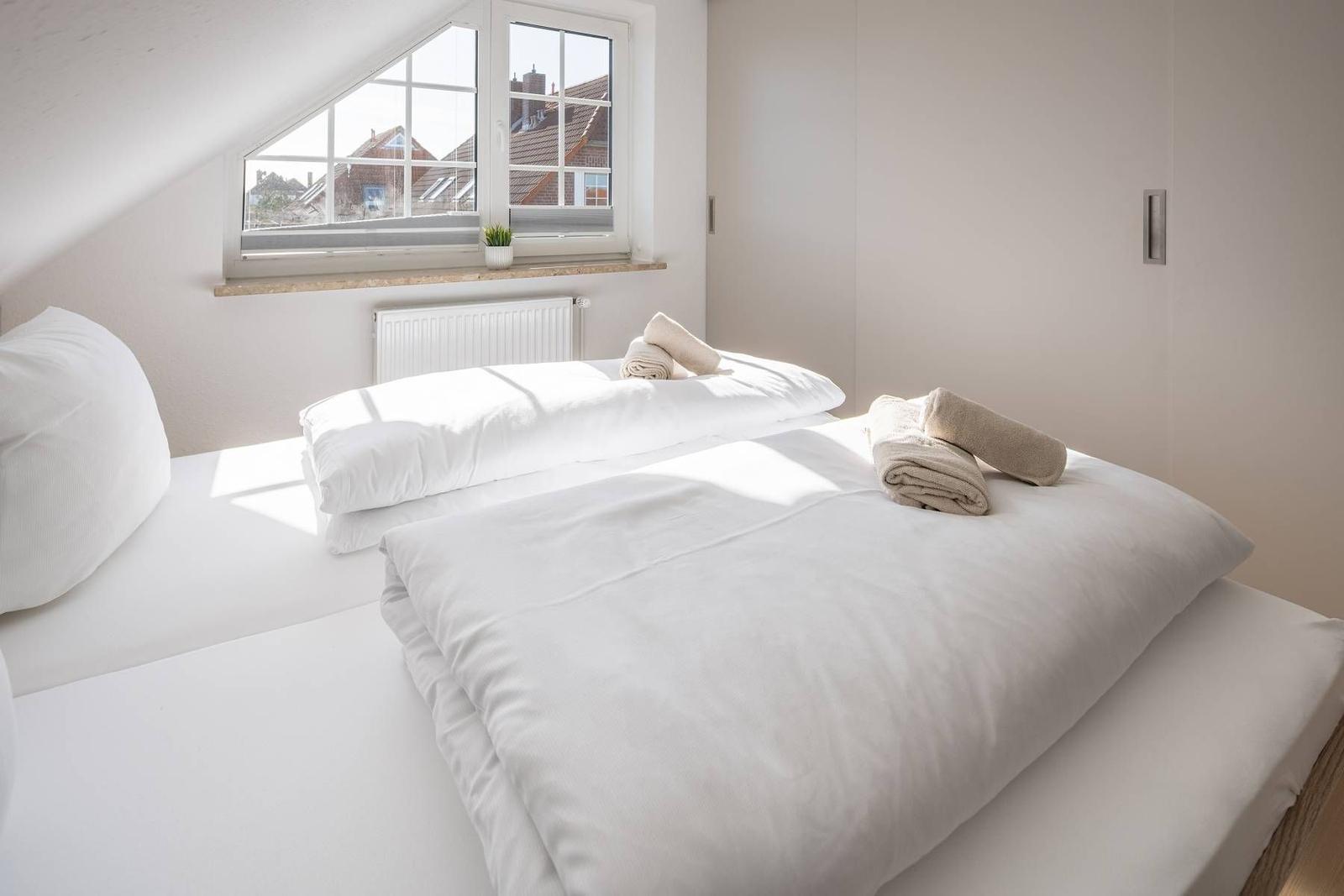 Schlafzimmer mit Dachfenster, Bett und Handtüchern
