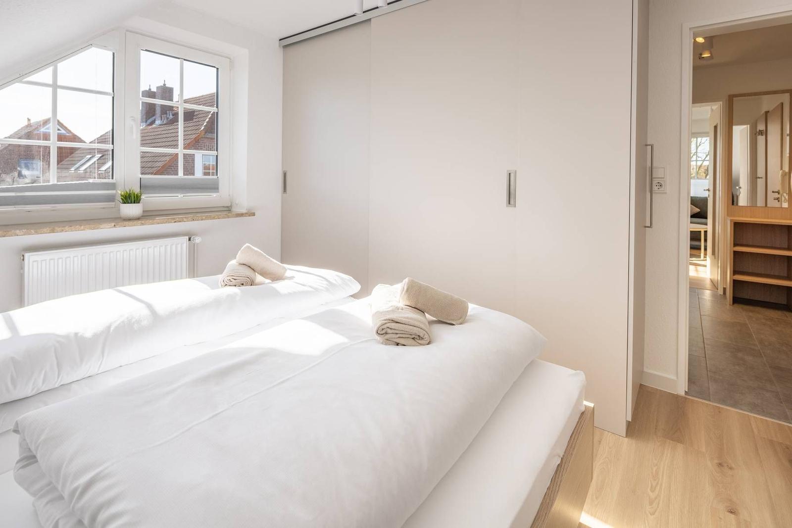 Schlafzimmer mit Doppelbett, Fenster und Schlafzimmerausgang.