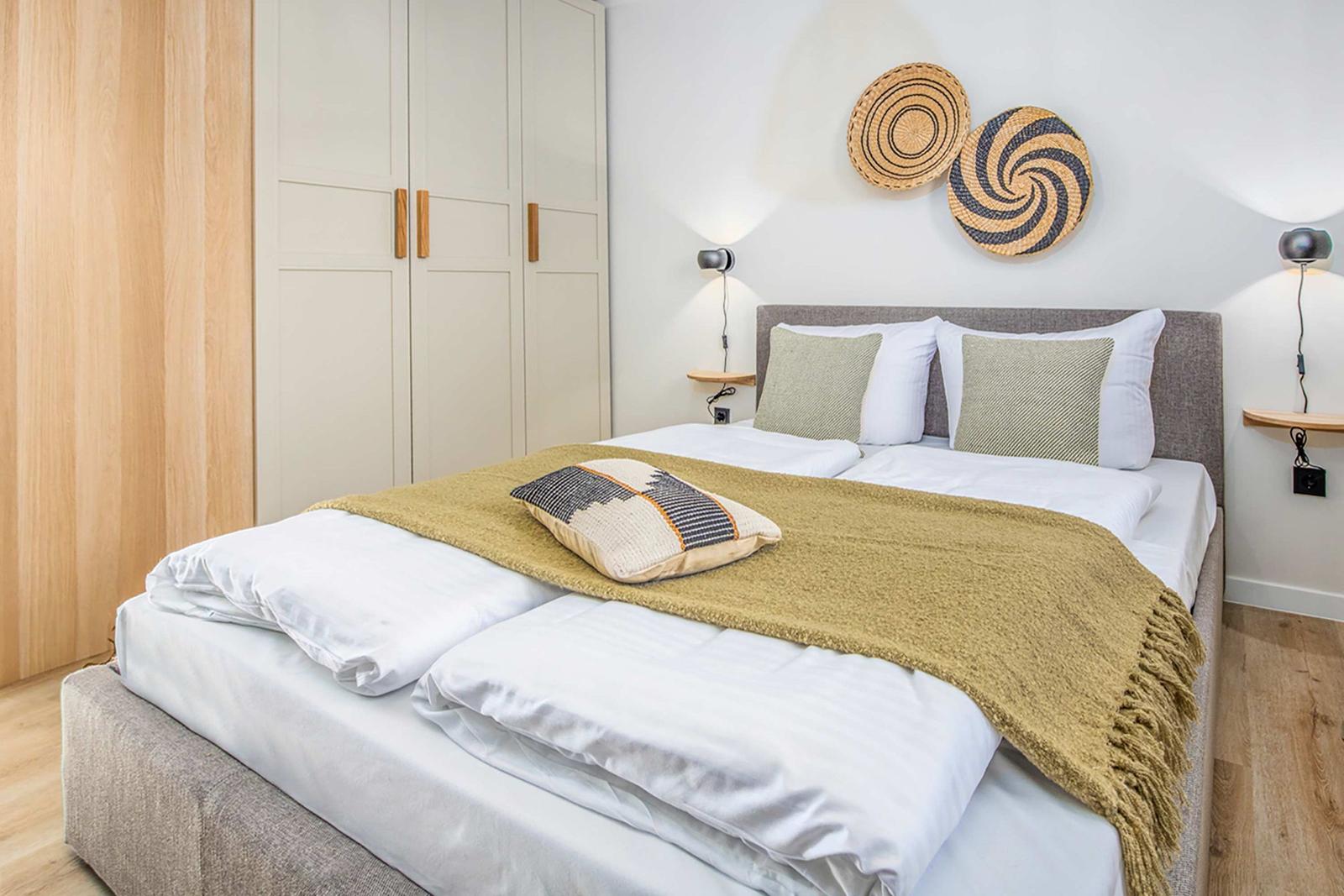 Double bed with white linens, green throw blanket, and wall decor.