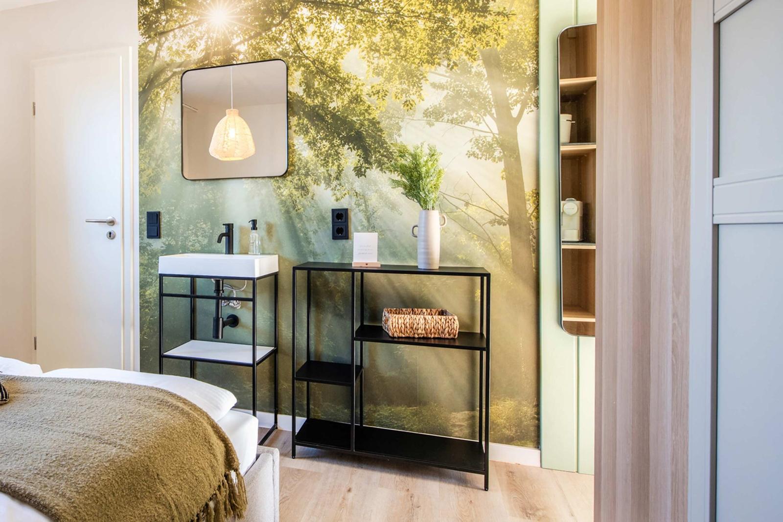 Bedroom with forest wallpaper, sink, and shelf. Bed with blanket visible.