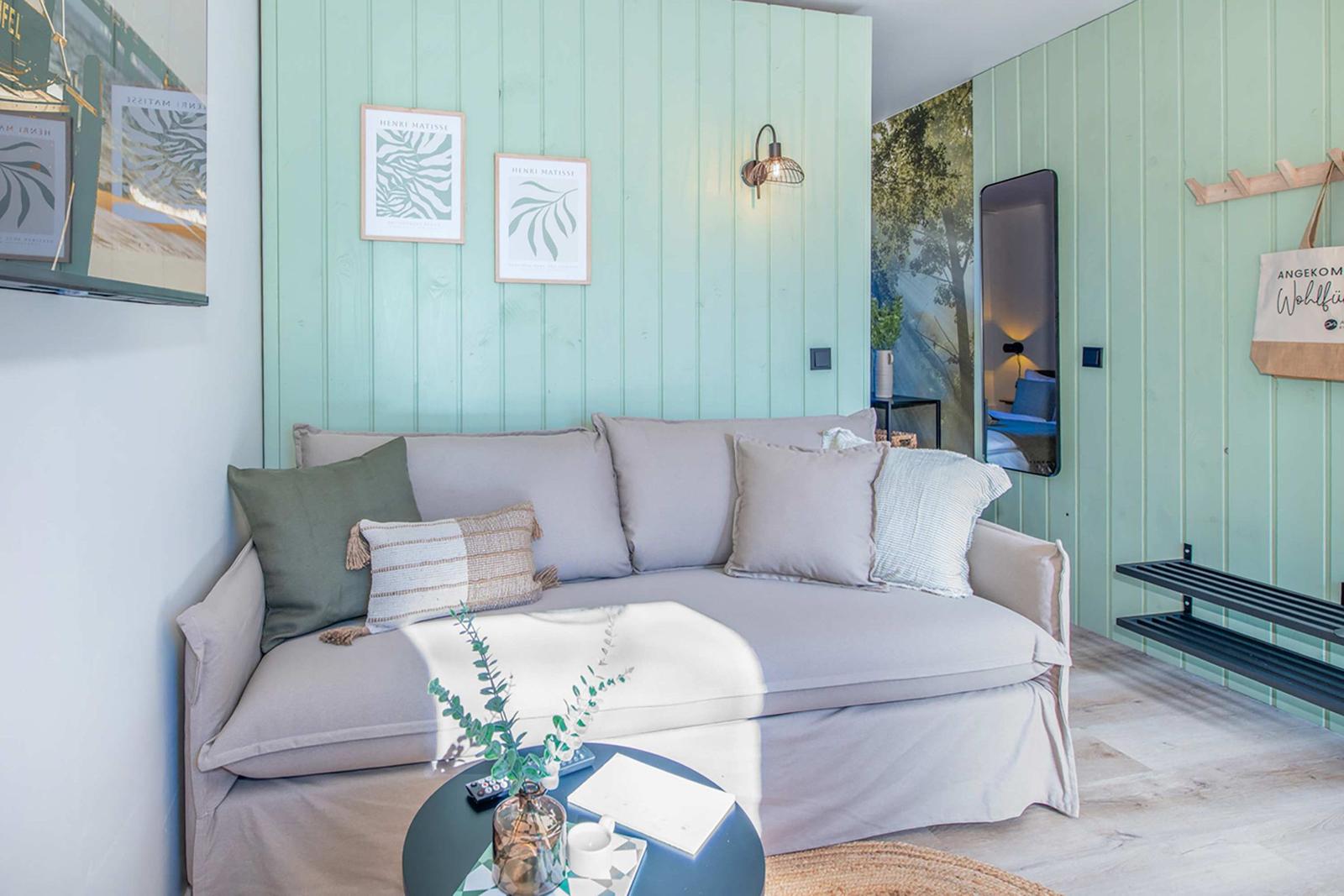 A living room with sofa, wall art, and green wood paneling