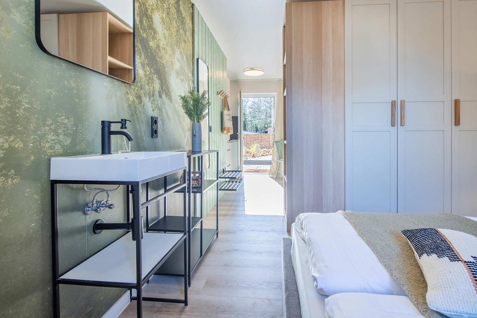 Bedroom with bed, wardrobe, and sink in hallway.