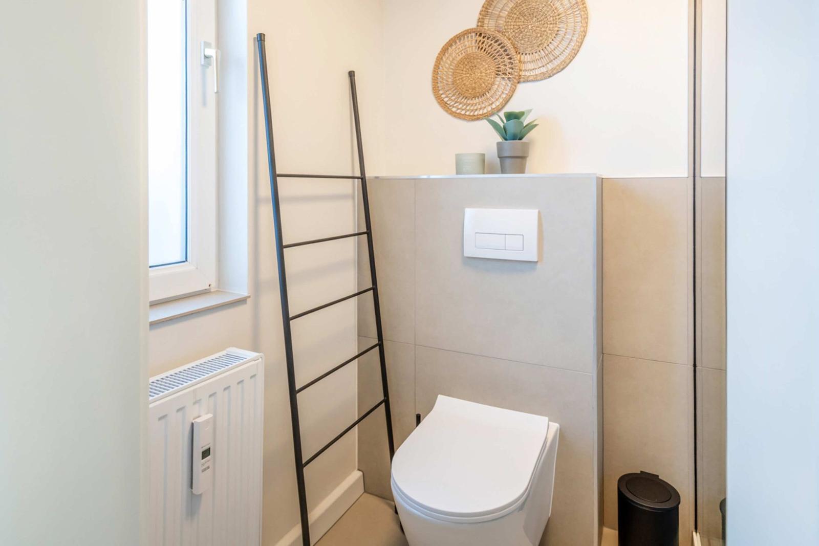 Toilet with window, radiator, and decorative wall elements.