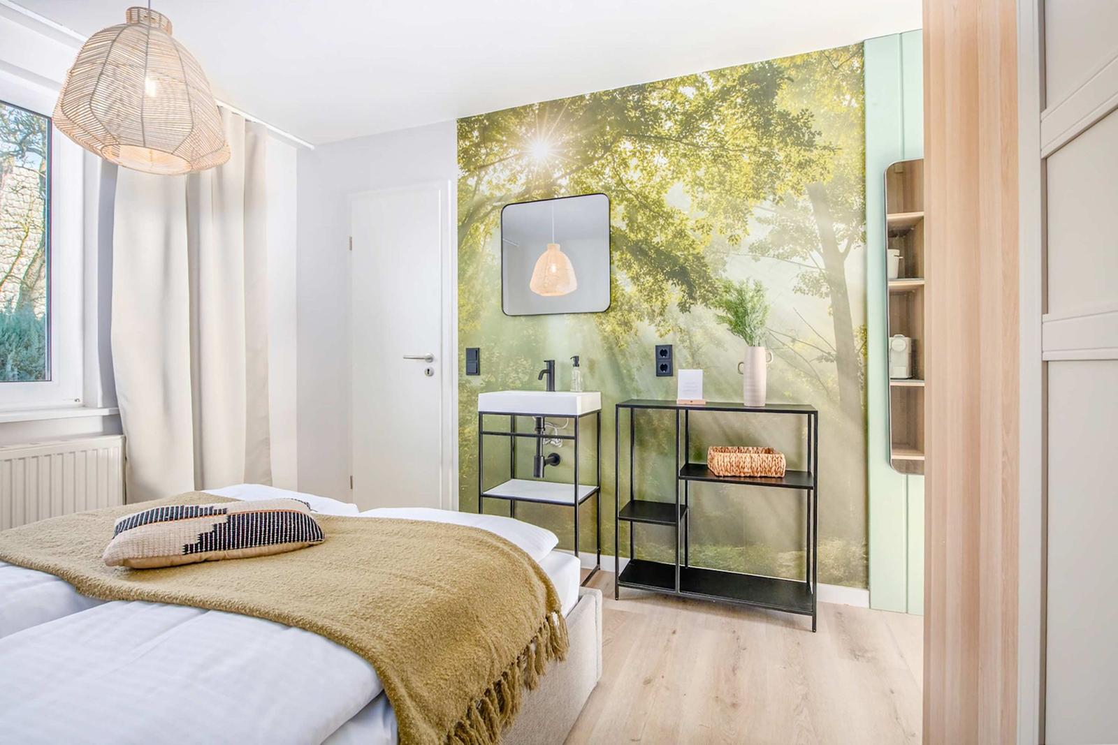 Bedroom with bed, wall mural, and sink. Wooden floor and window.