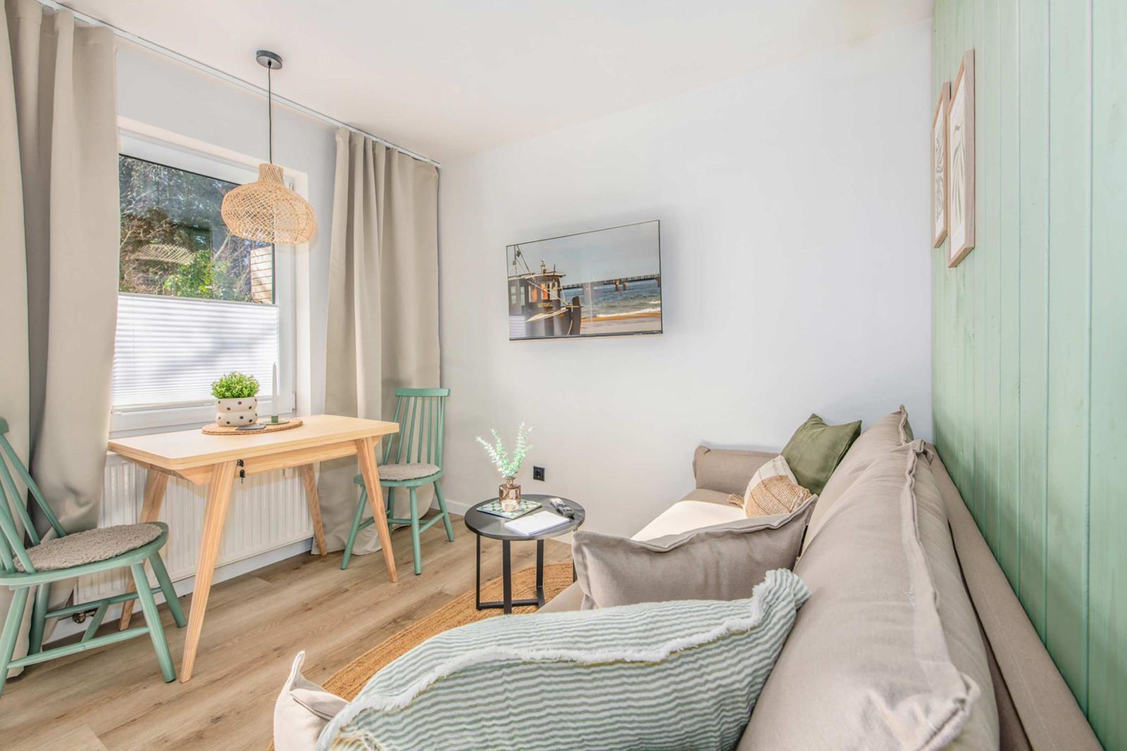 Living area with sofa, table, and chairs. Wall art and wooden floor.