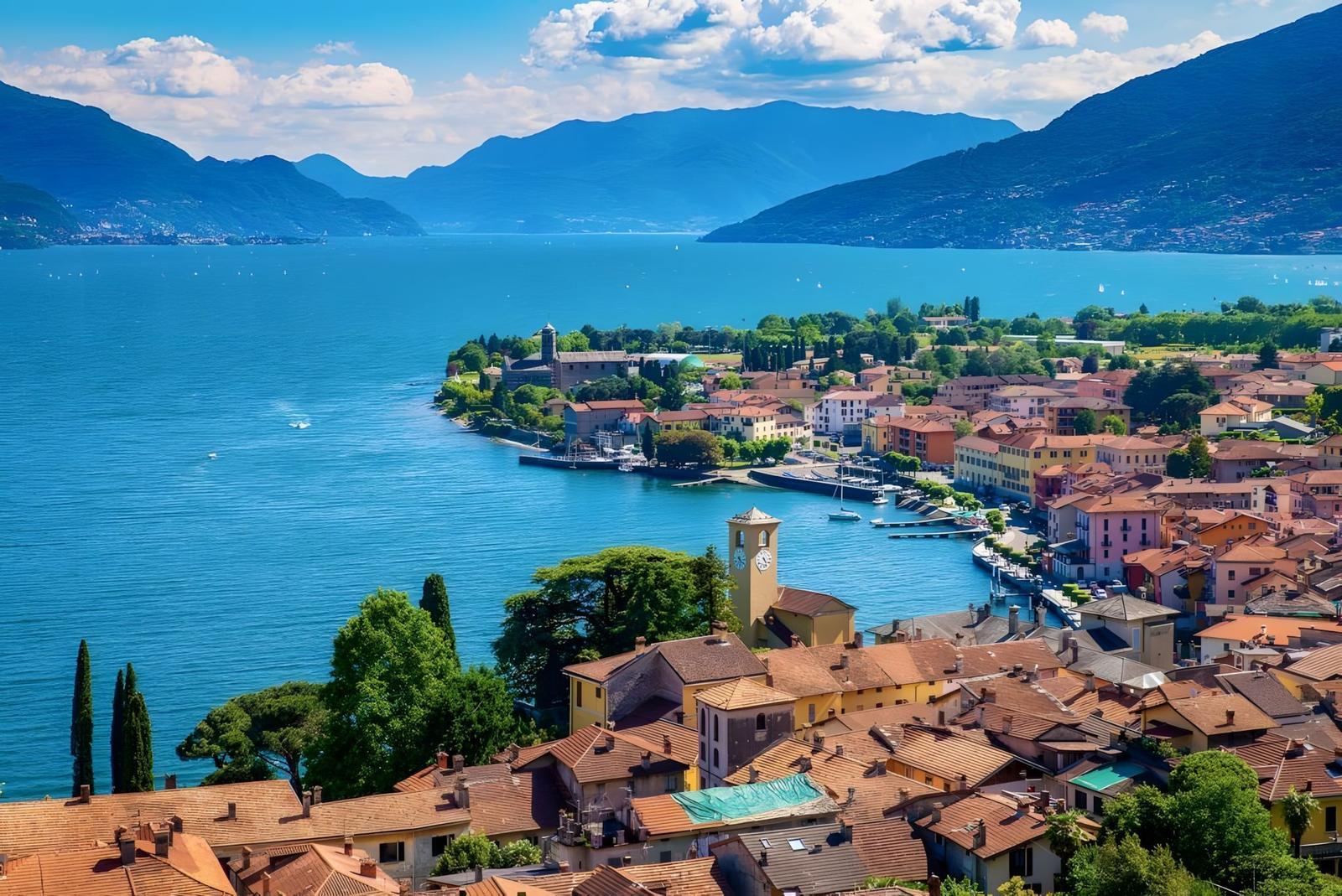 Panoramablick auf einen See mit Stadt und Bergen im Hintergrund.