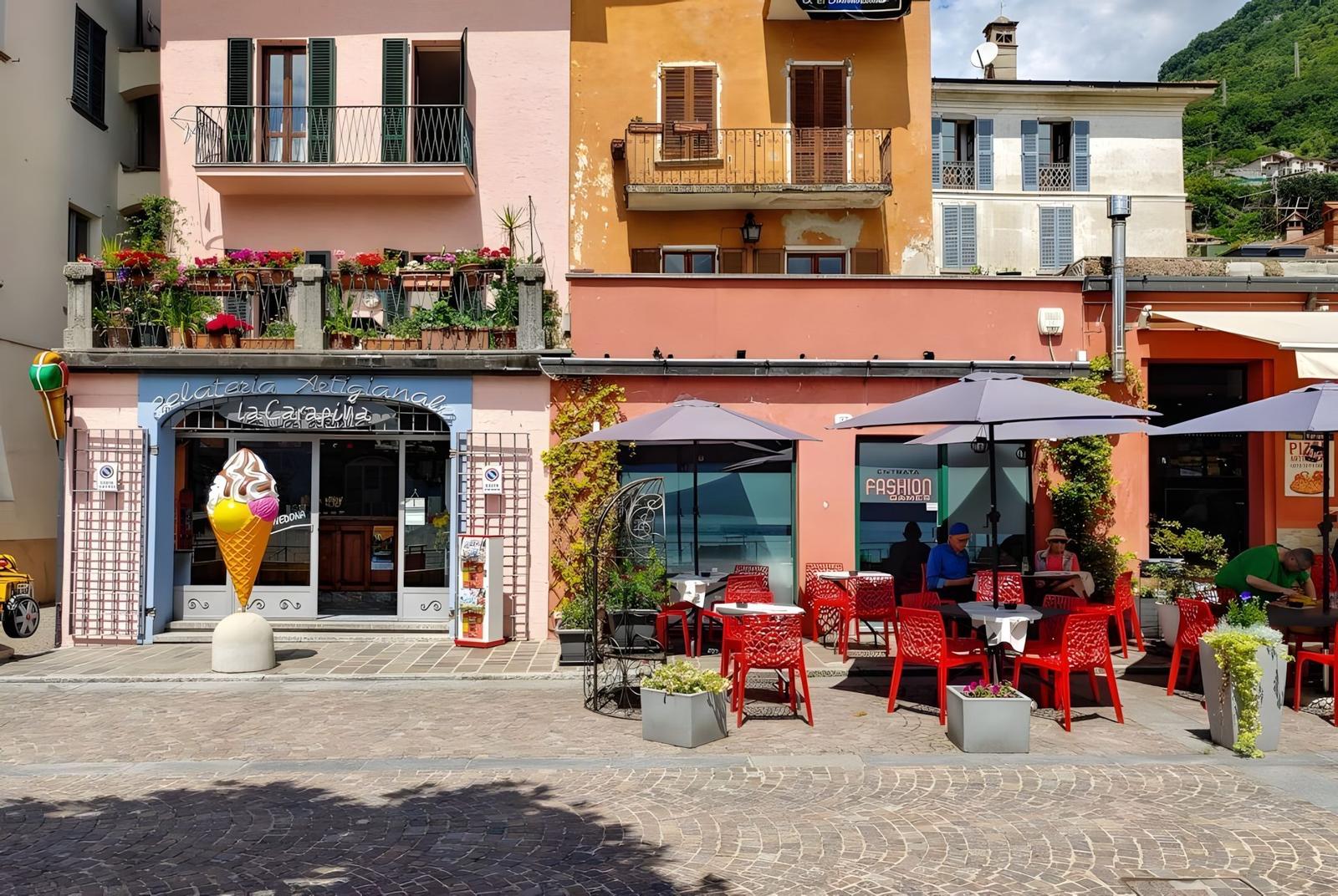 Gelateria mit Sitzgelegenheiten und farbenfrohen Gebäuden im Hintergrund.