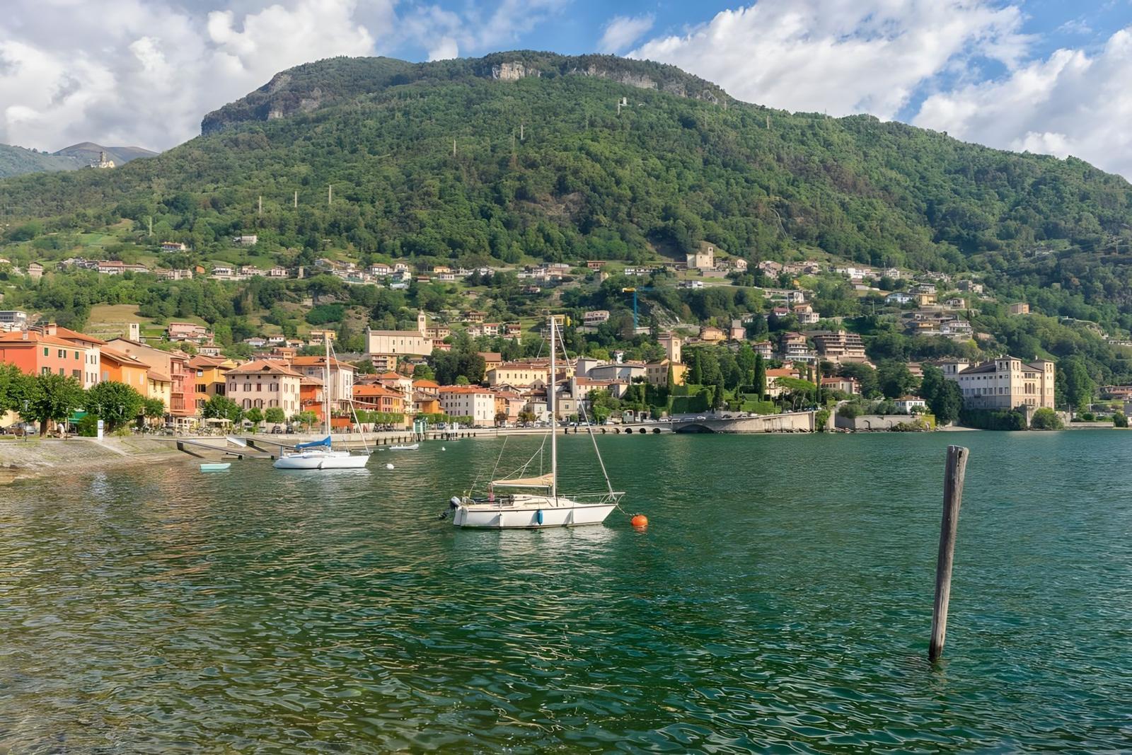 Boot liegt im See vor einer malerischen Bergstadt mit Häusern und einem Kirchturm.