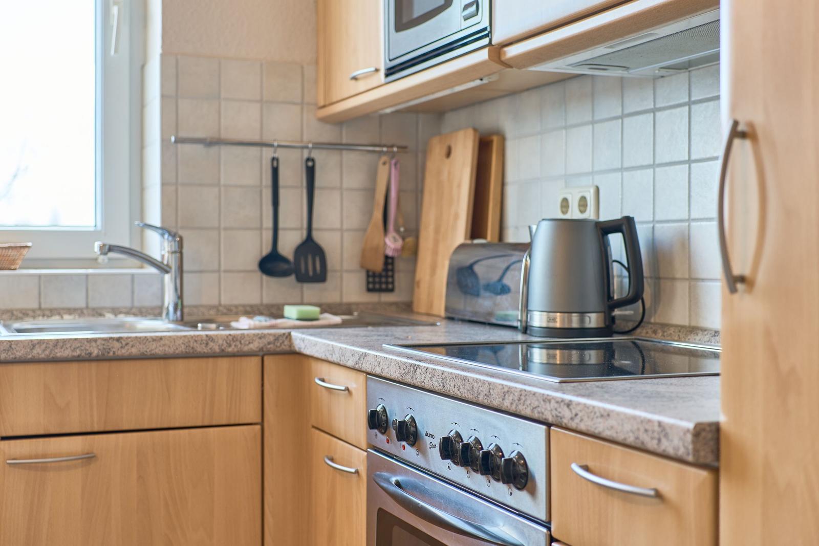 Küche mit Spüle, Herd, Kühlschrank und Küchenutensilien.