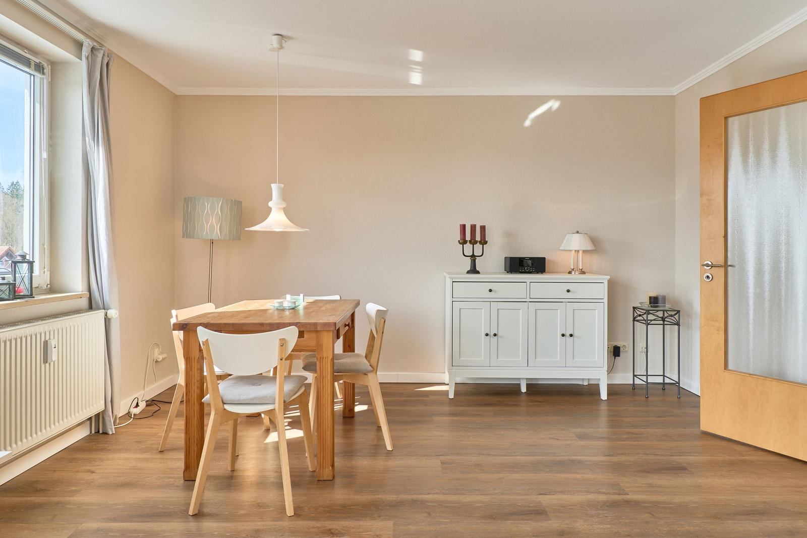 Esszimmer mit Holztisch, Stühlen, Sideboard und Fenster.