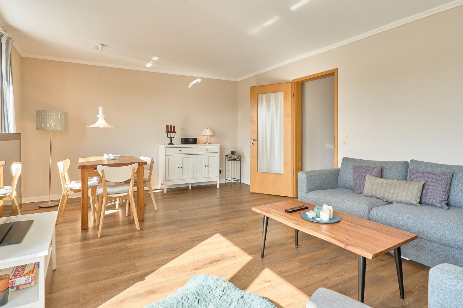Wohn- und Essbereich mit Holzboden, Sofa, Tisch und Stühlen.