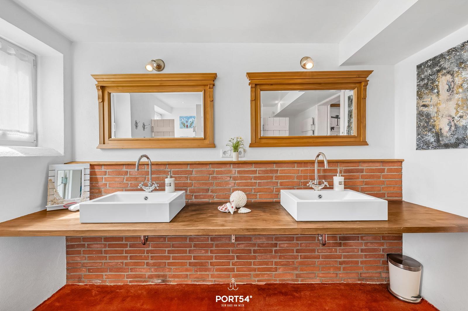 Zwei Waschbecken mit Spiegeln und Backsteinwand im Badezimmer