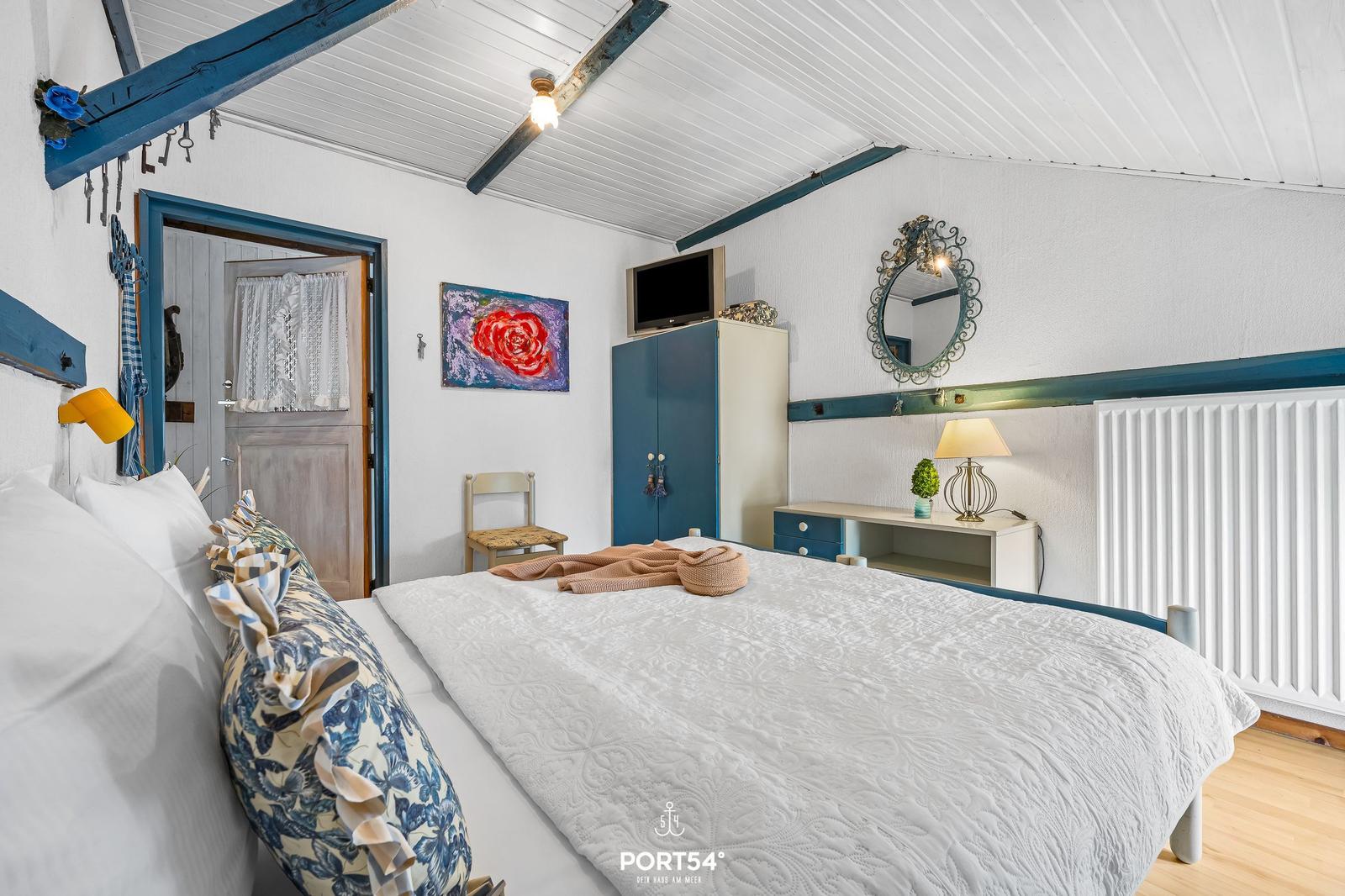 Schlafzimmer mit Bett, Schrank und Spiegel an der Wand.