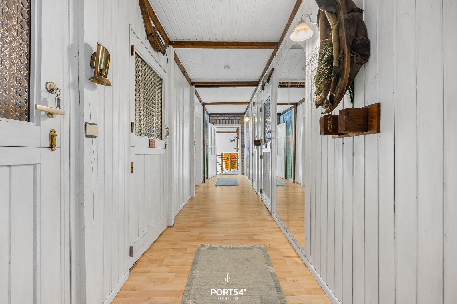 Langgang mit weißen Türen und Holzboden, Wanddekoration und Teppich