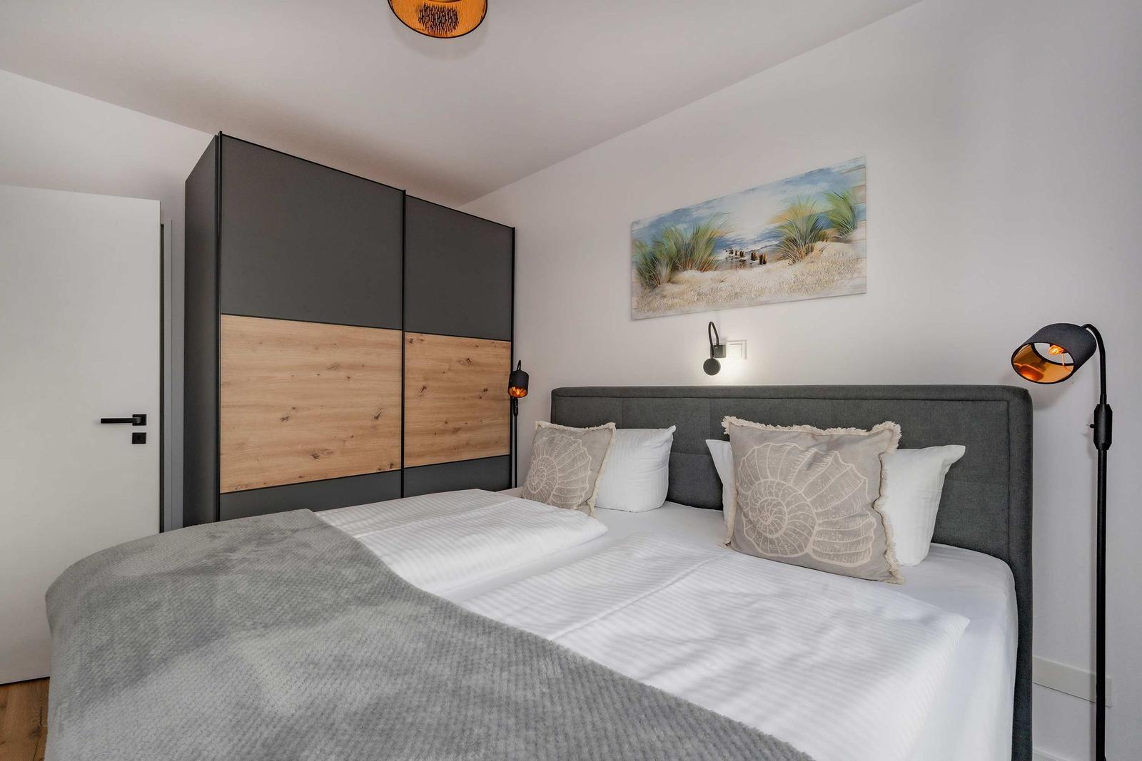 Schlafzimmer mit Doppelbett, Kleiderschrank und Wandbild.
