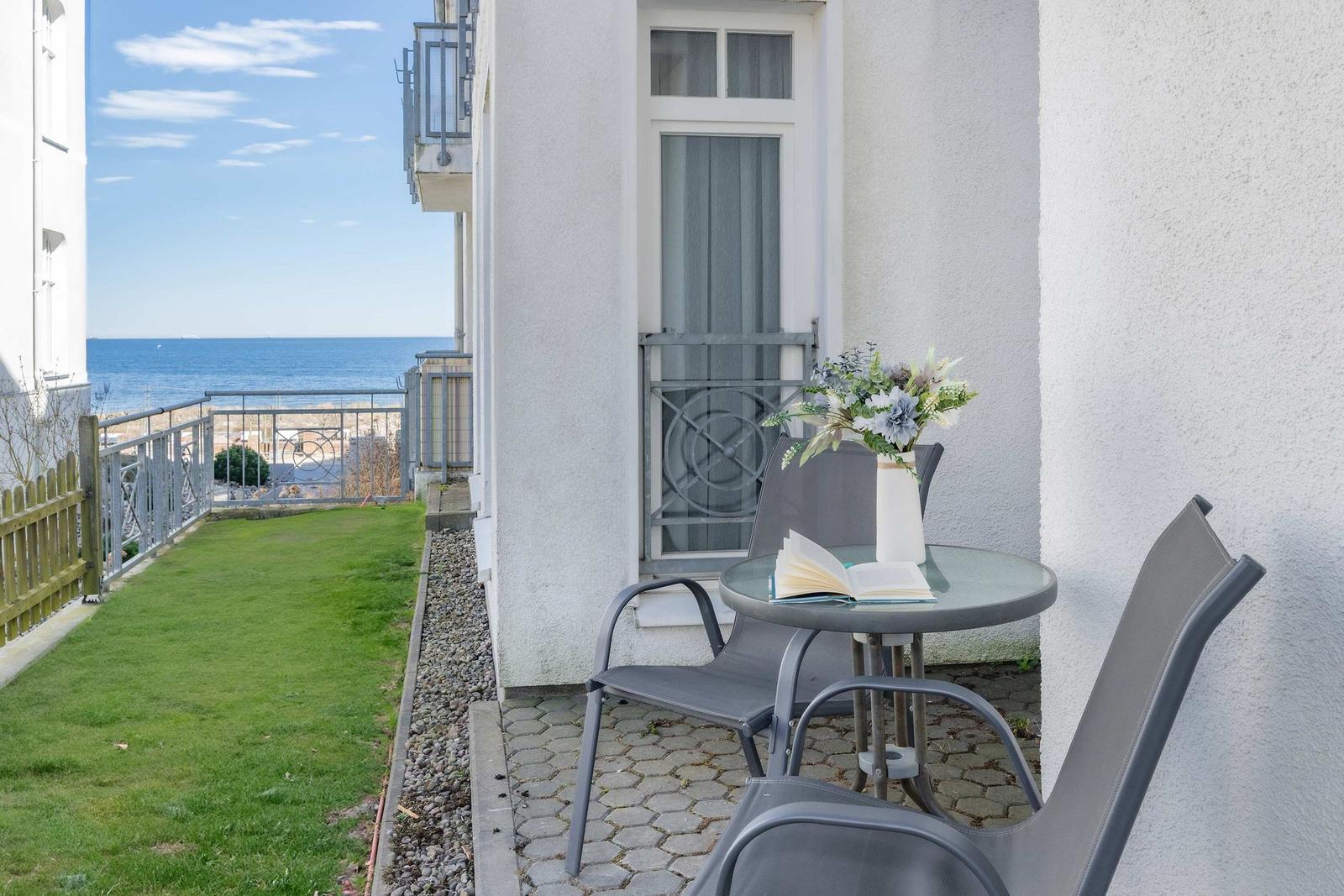Terrasse mit Tisch, Stühlen und Blick aufs Meer.