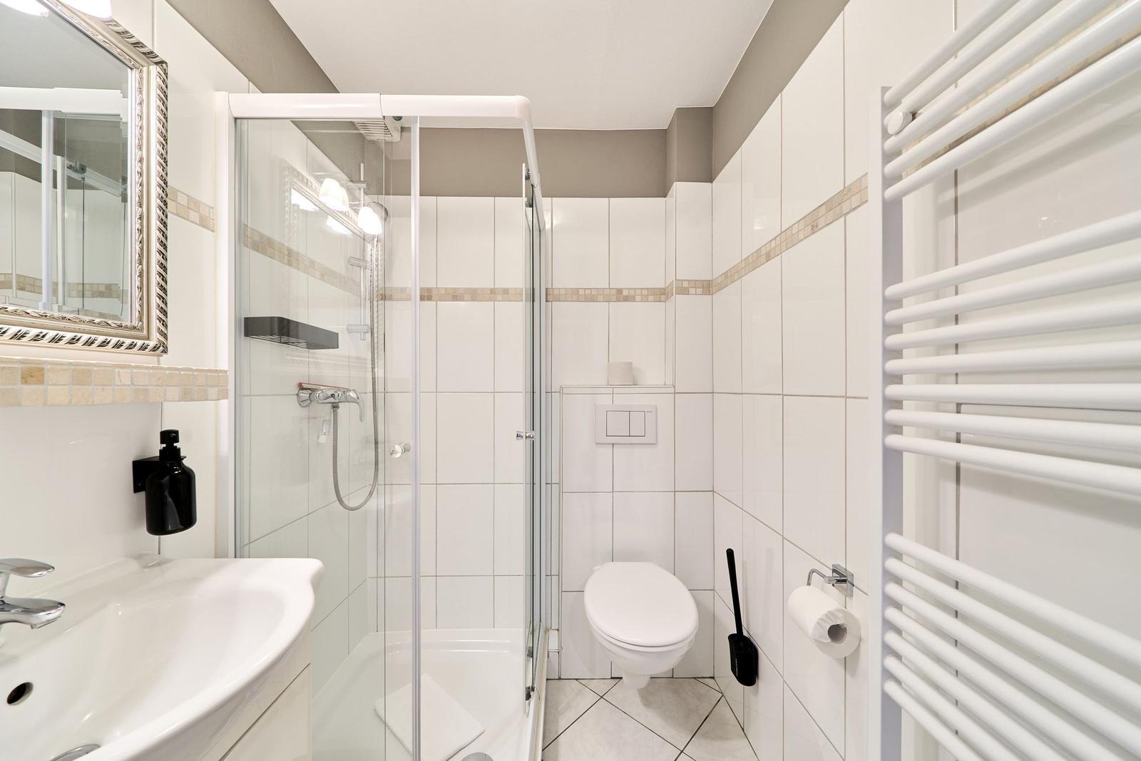 Badezimmer mit Dusche, Toilette und Handtuchheizung.
