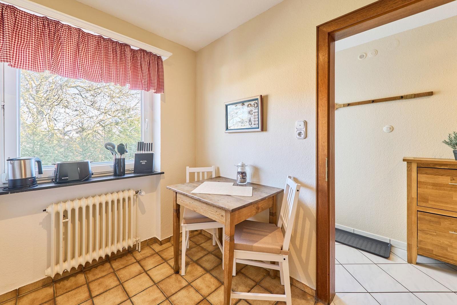 Essbereich mit Tisch, Stühlen und Fenster mit Blick auf Bäume.