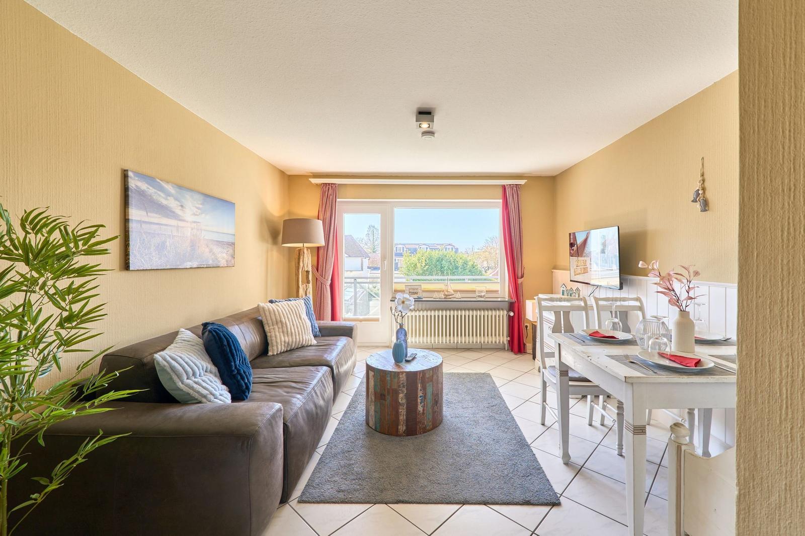 Wohn- und Essbereich mit Sofa, Tisch und Fensterblick.