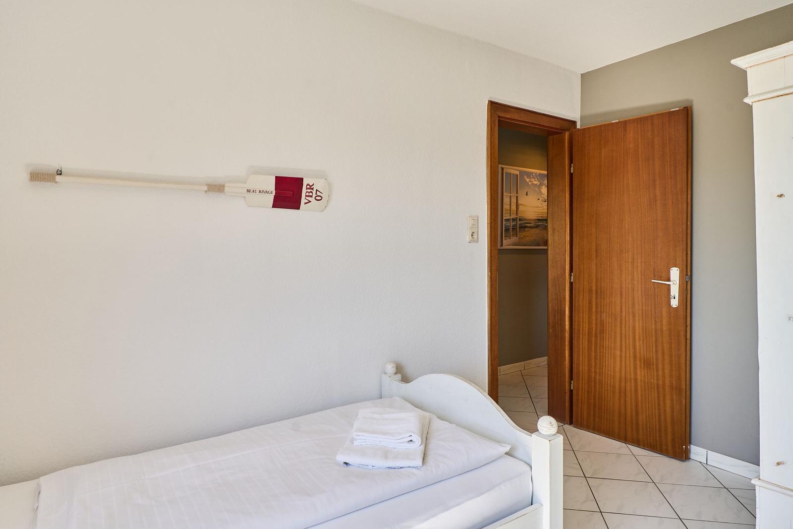 Ein Schlafzimmer mit weißem Bett, Holztür und Wanddekoration.