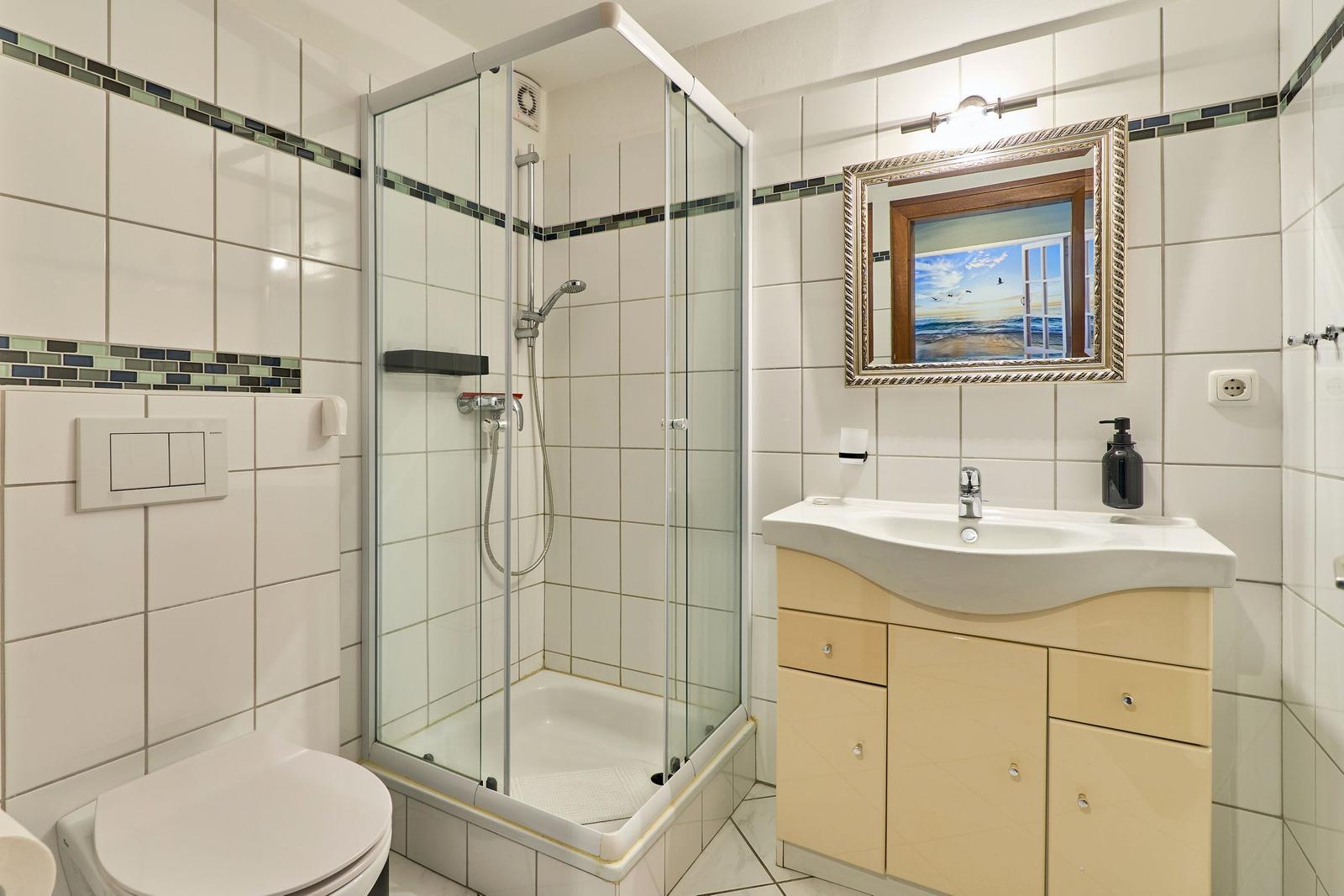 Badezimmer mit Dusche, Waschbecken und Spiegel