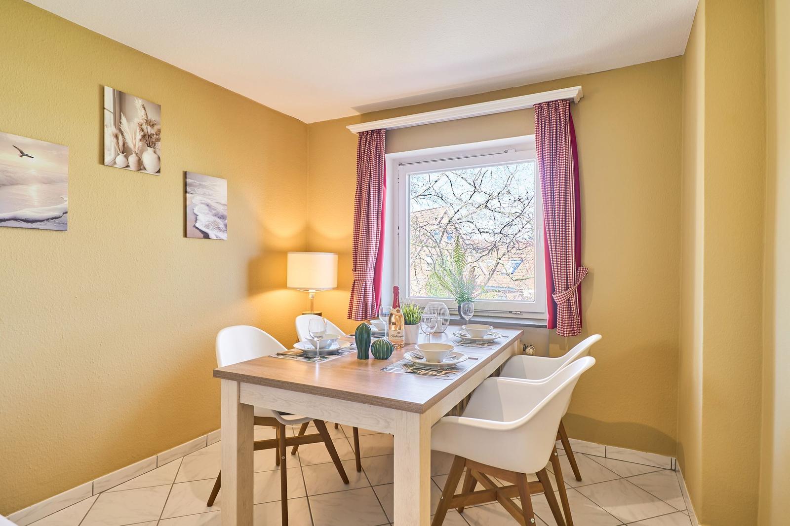 Esszimmer mit Tisch, Stühlen und Fenster mit Blick auf Außenbereich.
