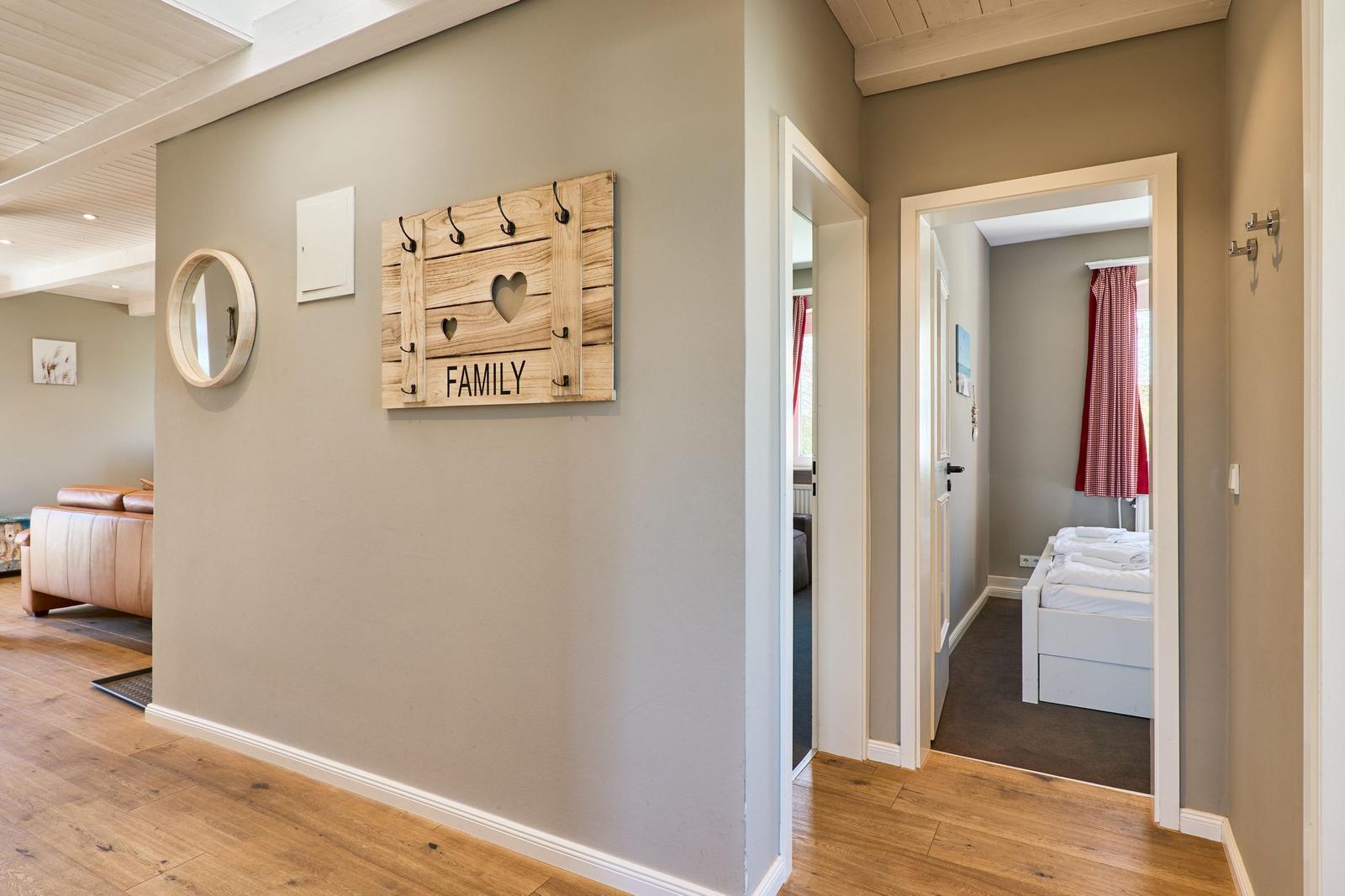Hausflur mit Wanddekoration und Blick in Schlafzimmer mit Bett und Fenster.
