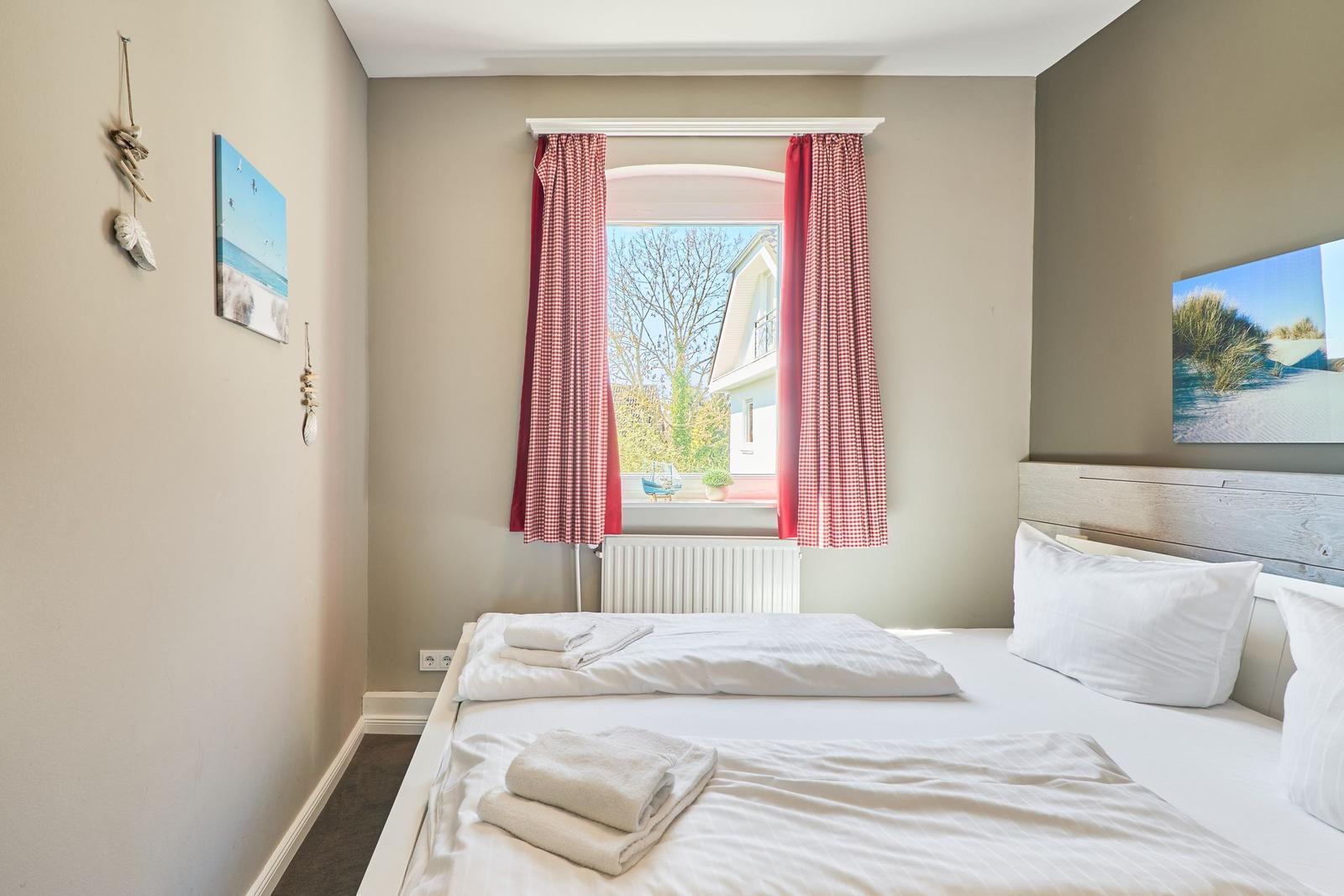 Schlafzimmer mit Bett, Fenster und Wandbildern