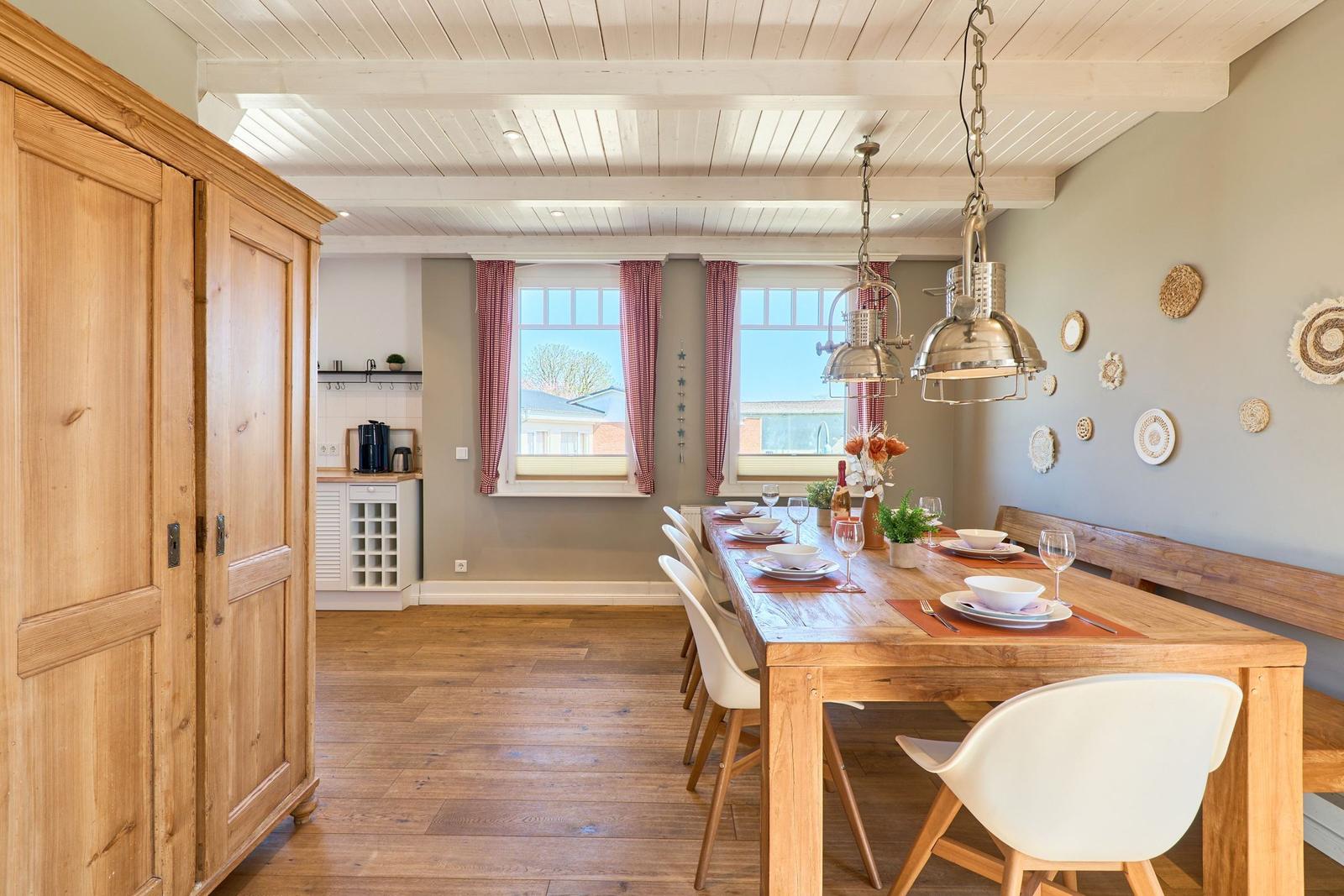 Esszimmer mit Holztisch, Stühlen und Fenstern mit roten Vorhängen.
