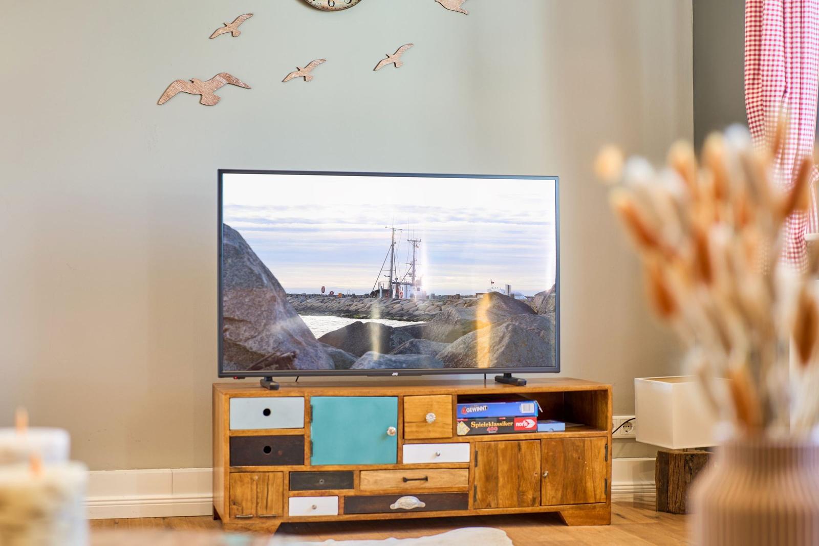 TV auf Holzregal mit farbigen Schubladen, Wanddekoration aus Holzvögeln