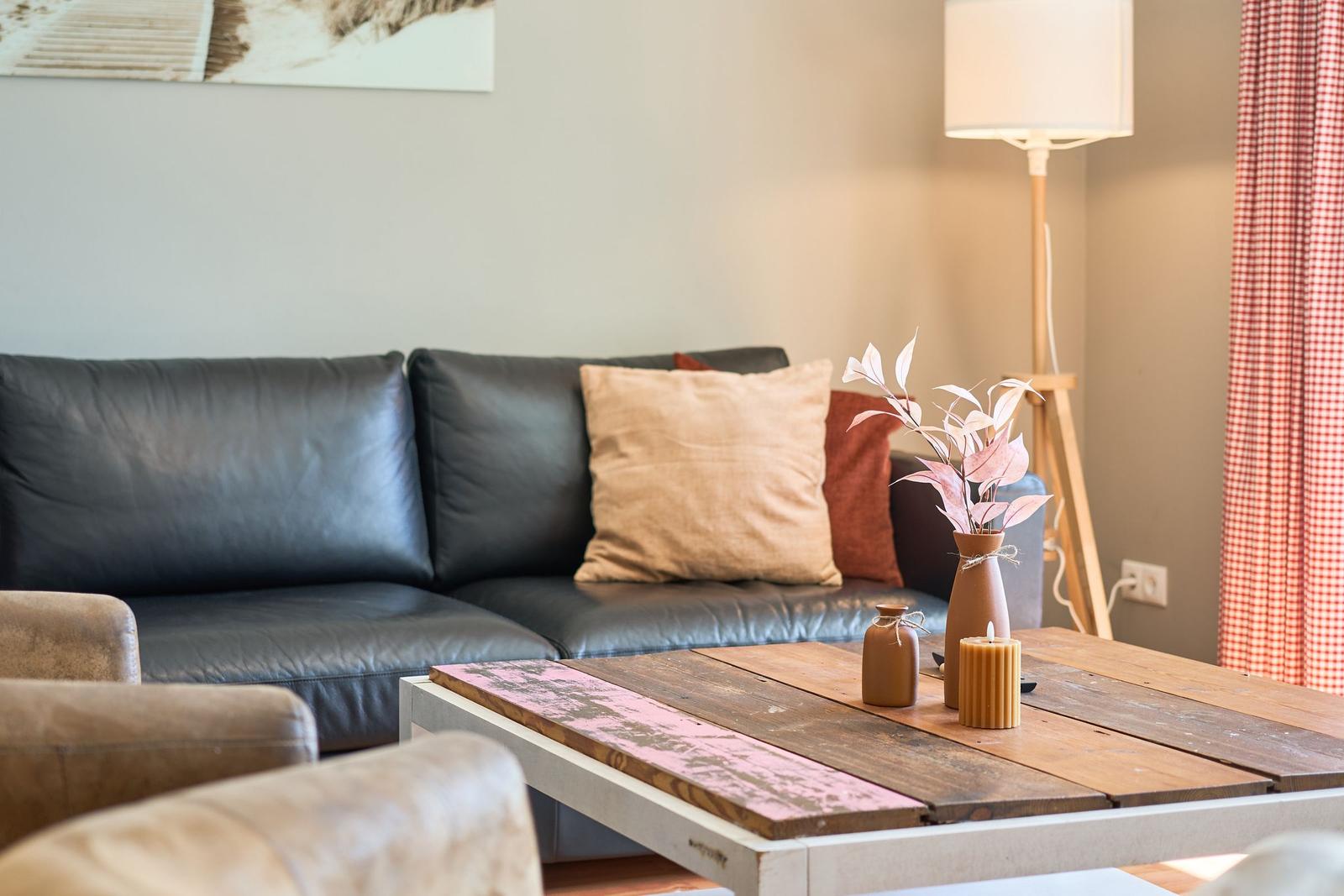Ein Wohnzimmer mit einem schwarzen Sofa, einem Holztisch und einer Stehlampe.