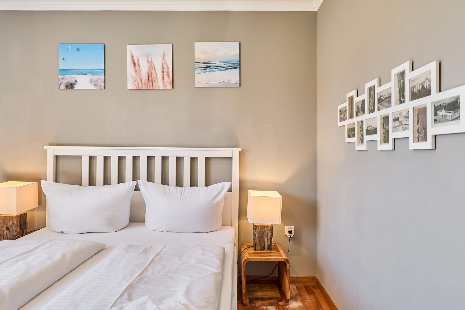 Schlafzimmer mit Bett, zwei Nachttischen und Wandbildern.