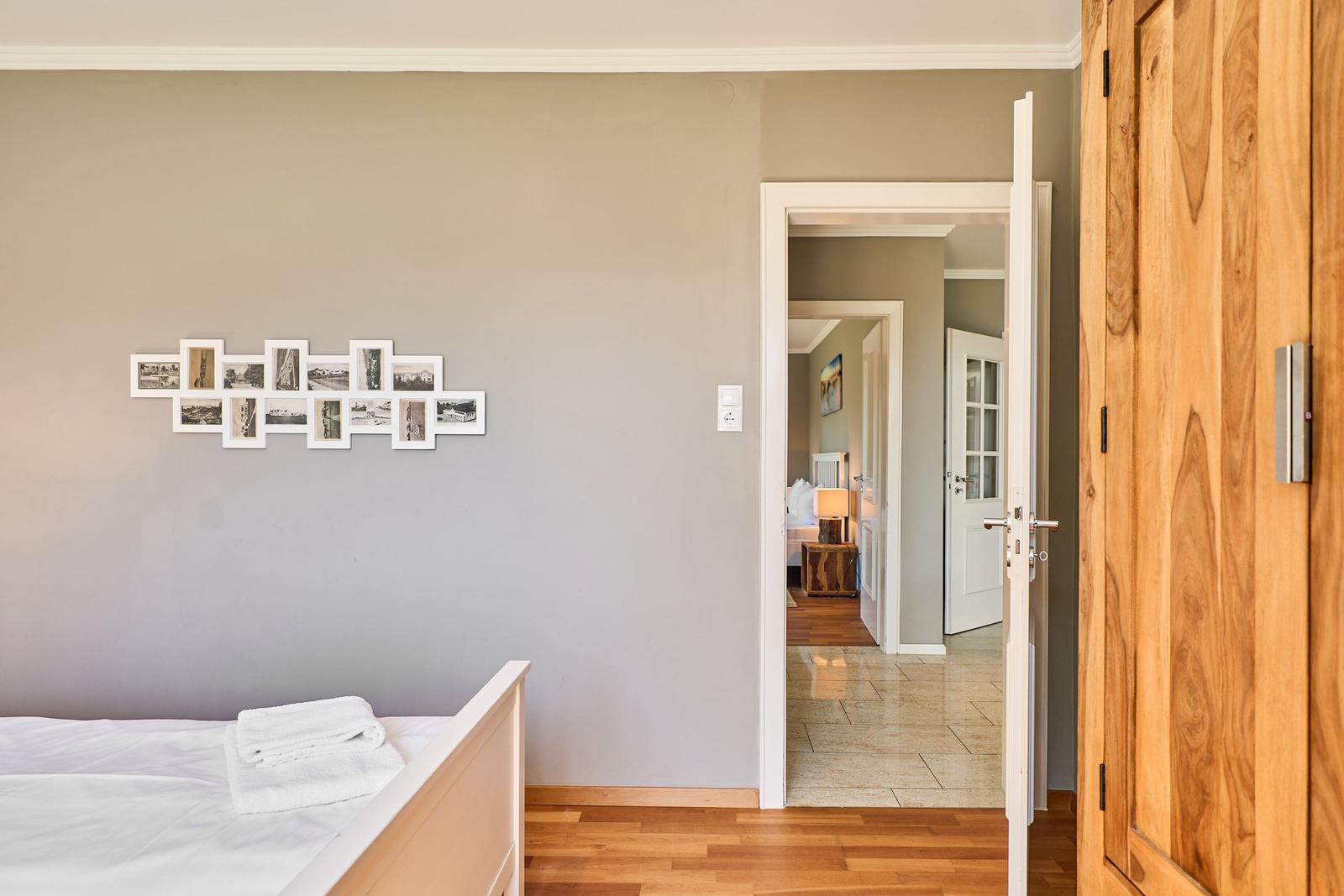 Schlafzimmer mit Bett, Holzboden und Wanddekoration. Tür führt in angrenzenden Raum.