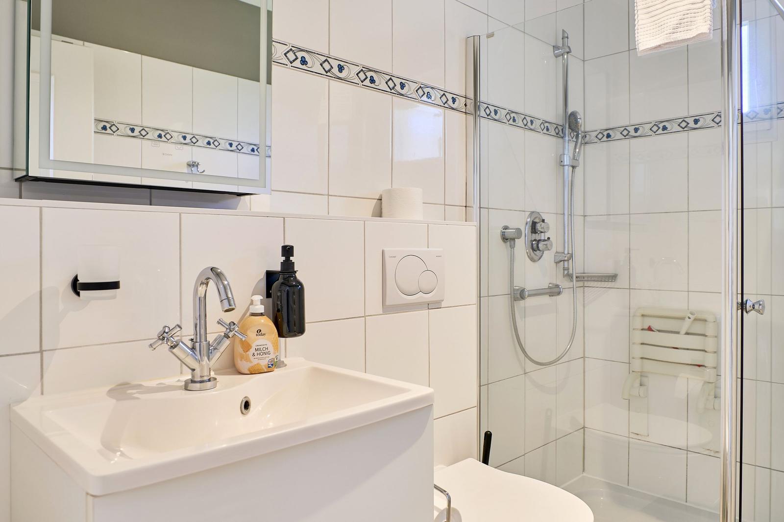 Badezimmer mit Dusche, Waschbecken und Spiegel