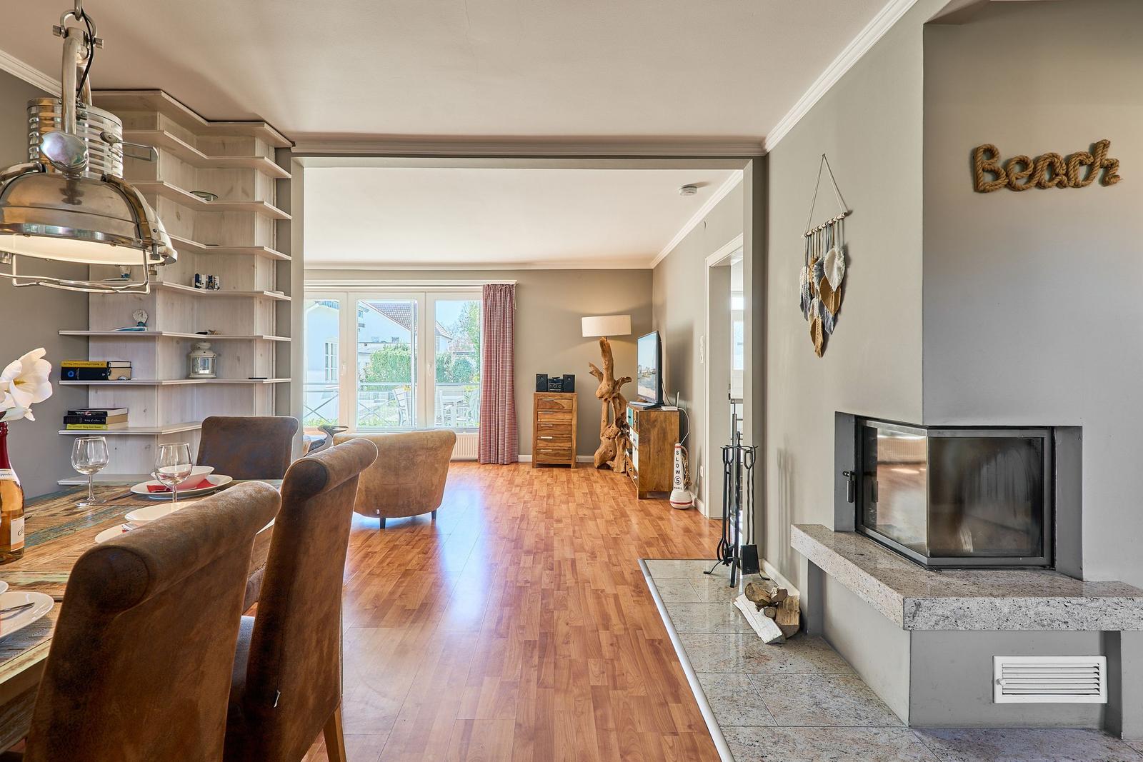 Essbereich mit Sitzgelegenheit, Wohnbereich mit Fernseher und Kamin. Holzboden und großes Fenster.