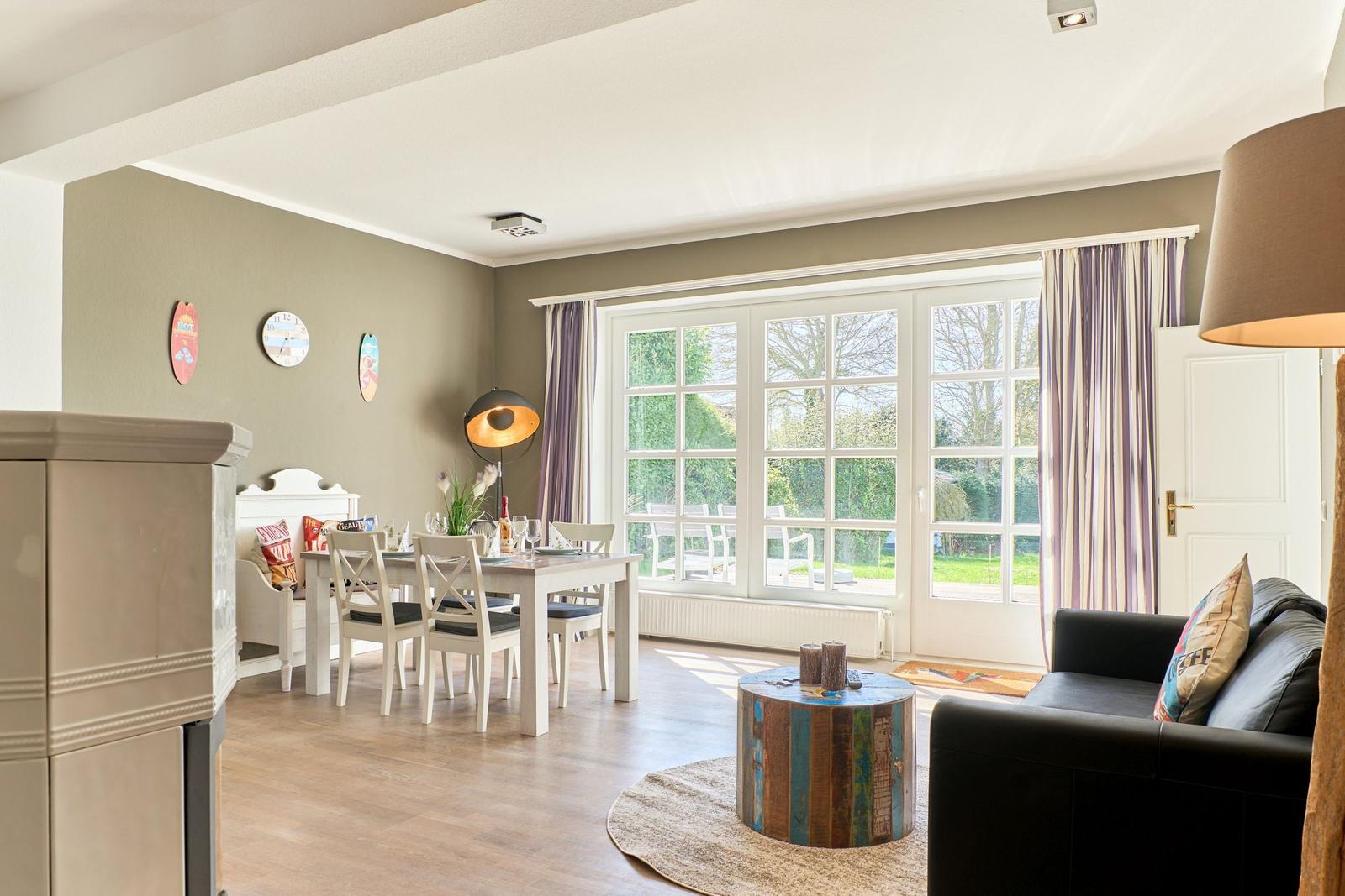 Wohn- und Essbereich mit großem Fenster, Tisch, Stühlen und Sofa.